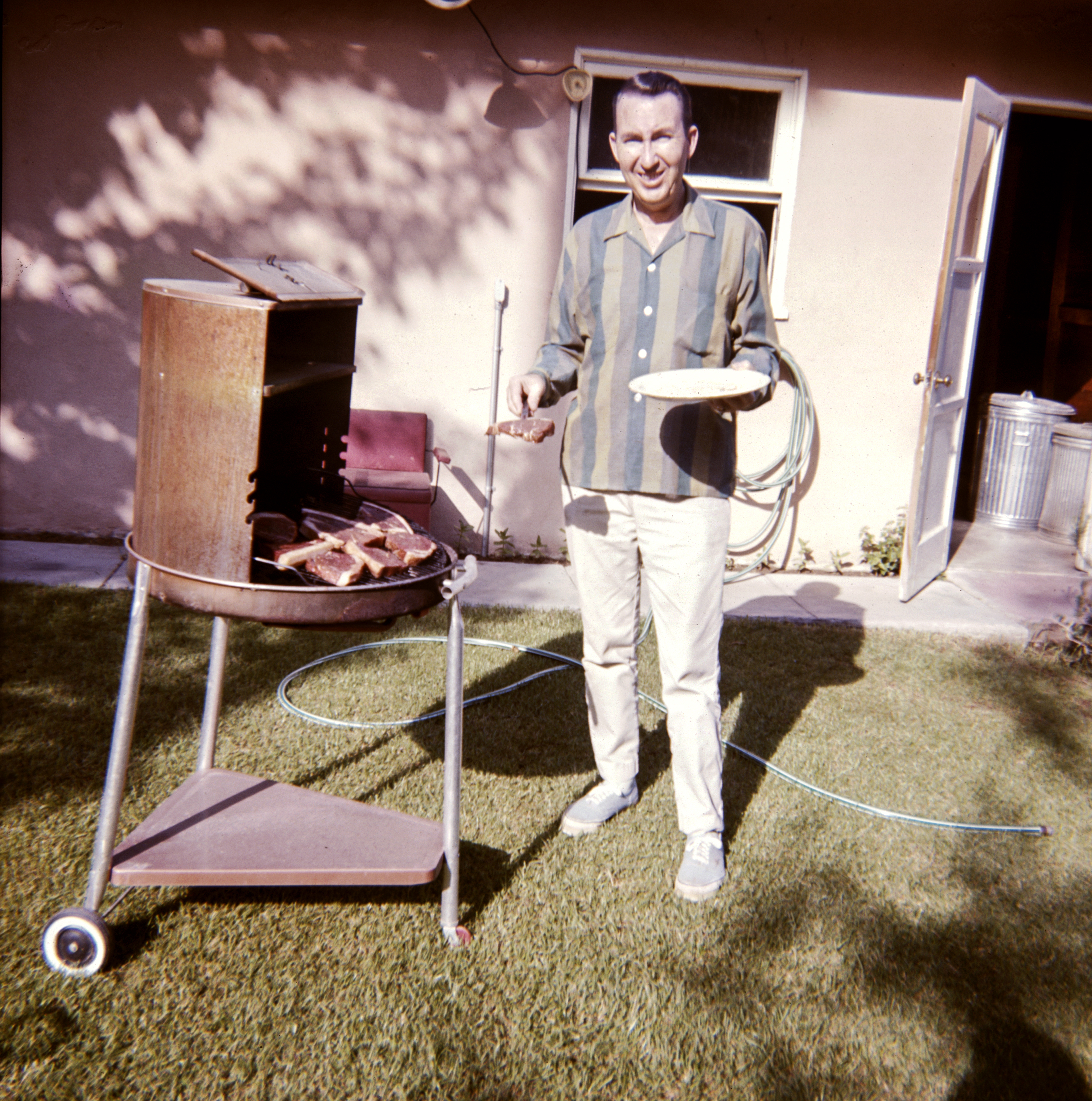 Caucasian man cooking meat on barbecue in yard