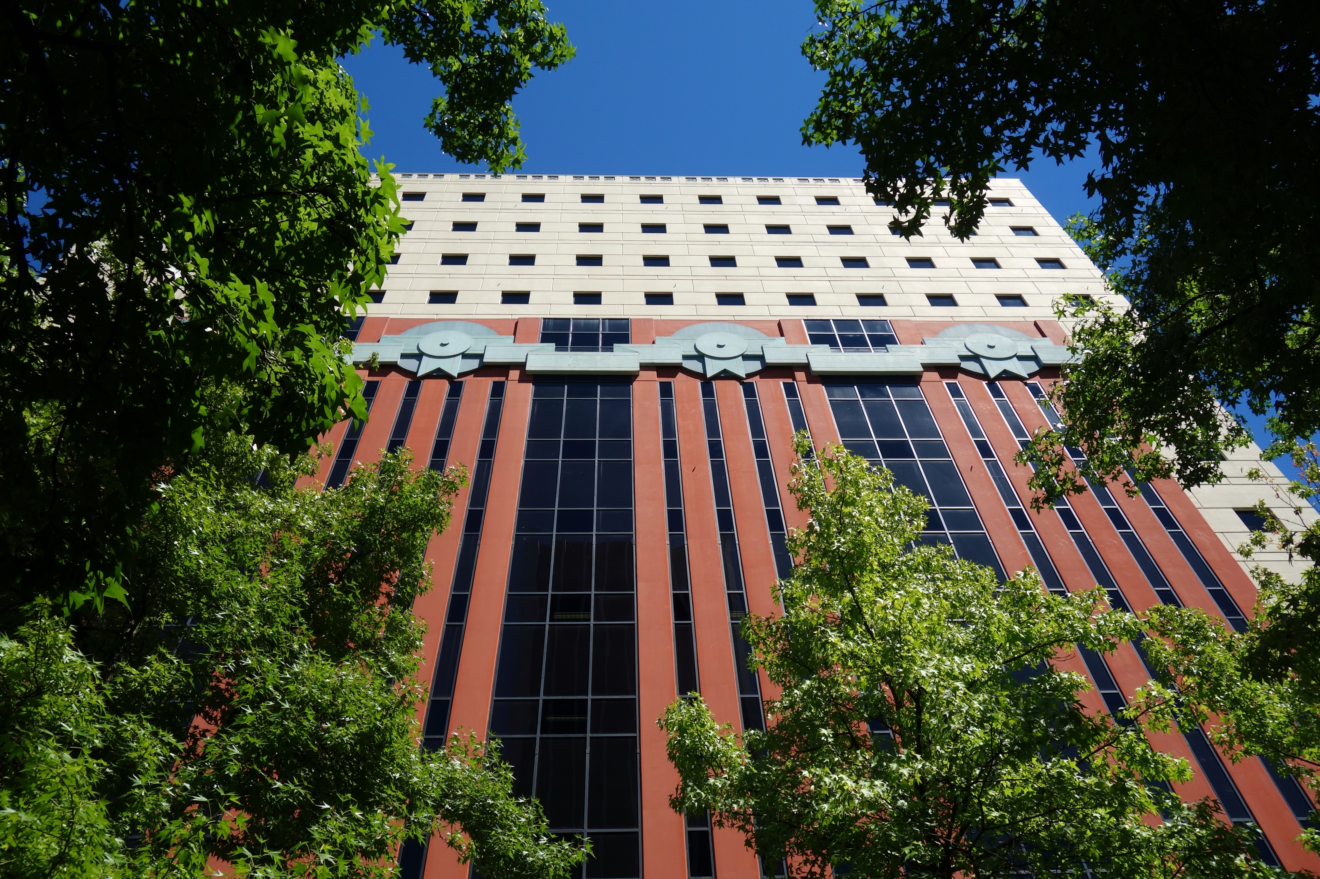 The exterior of a postmodern Portland building. The facade is red and white. There are trees in the foreground.