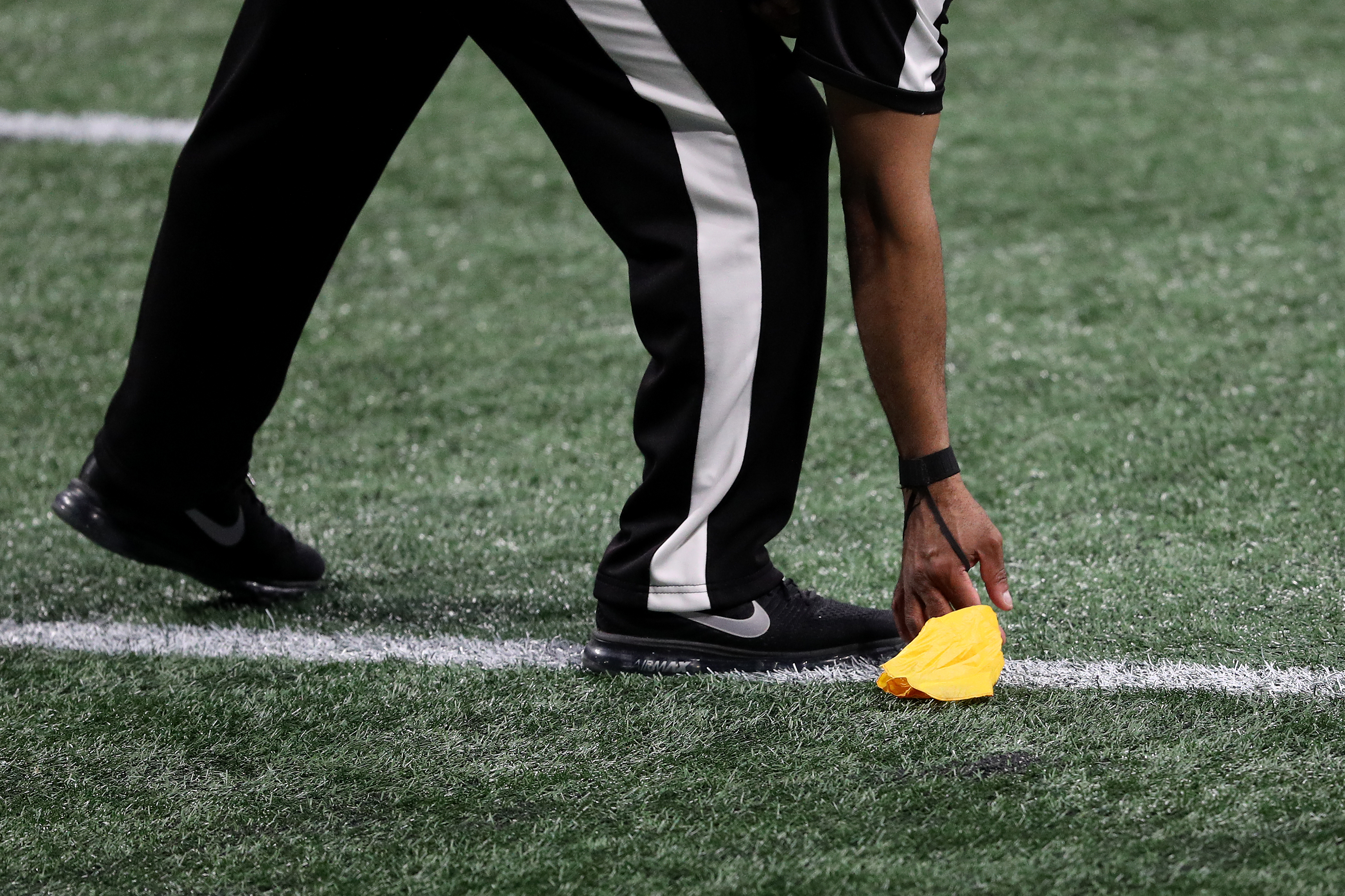 A referee picks up a flag in the first quarter during Super Bowl LIII between the Los Angeles Rams and New England Patriots, Feb. 3, 2019.