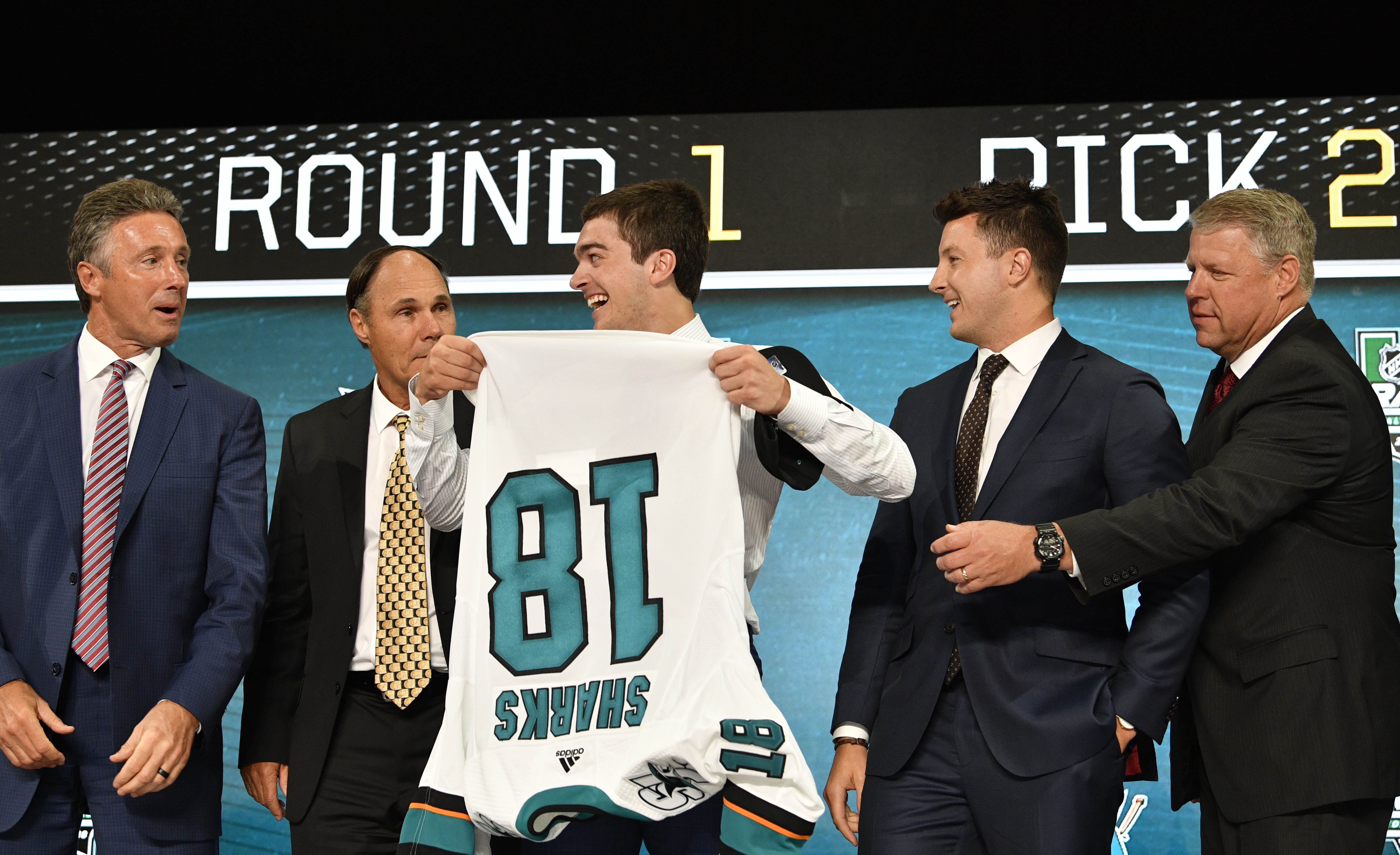 Jun 22, 2018; Dallas, TX, USA; Ryan Merkley puts on a team jersey after being selected as the number twenty-one overall pick to the San Jose Sharks in the first round of the 2018 NHL Draft at American Airlines Center.
