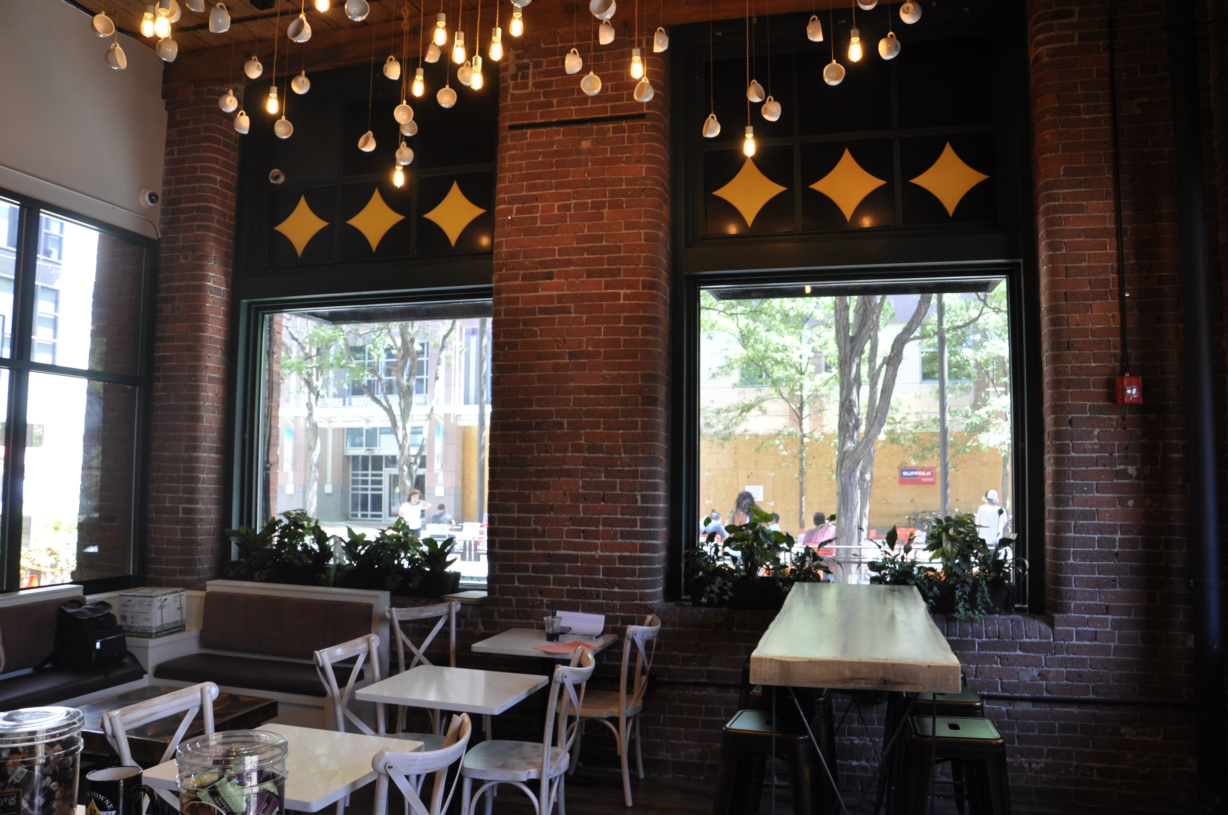 The interior of Beantowne Coffee House’s Kendall Square location, with bare lightbulbs and white coffee cups dangling from the ceiling.