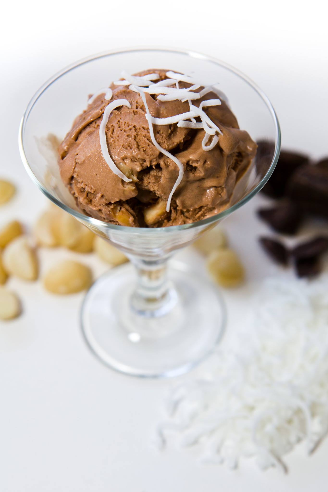 A glass of chocolate ice cream scoops topped with shredded white coconut