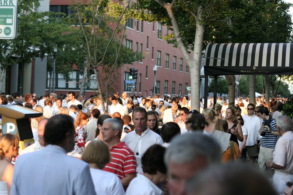 A large crowd of people wearing white flows through Julia Street in New Orleans.