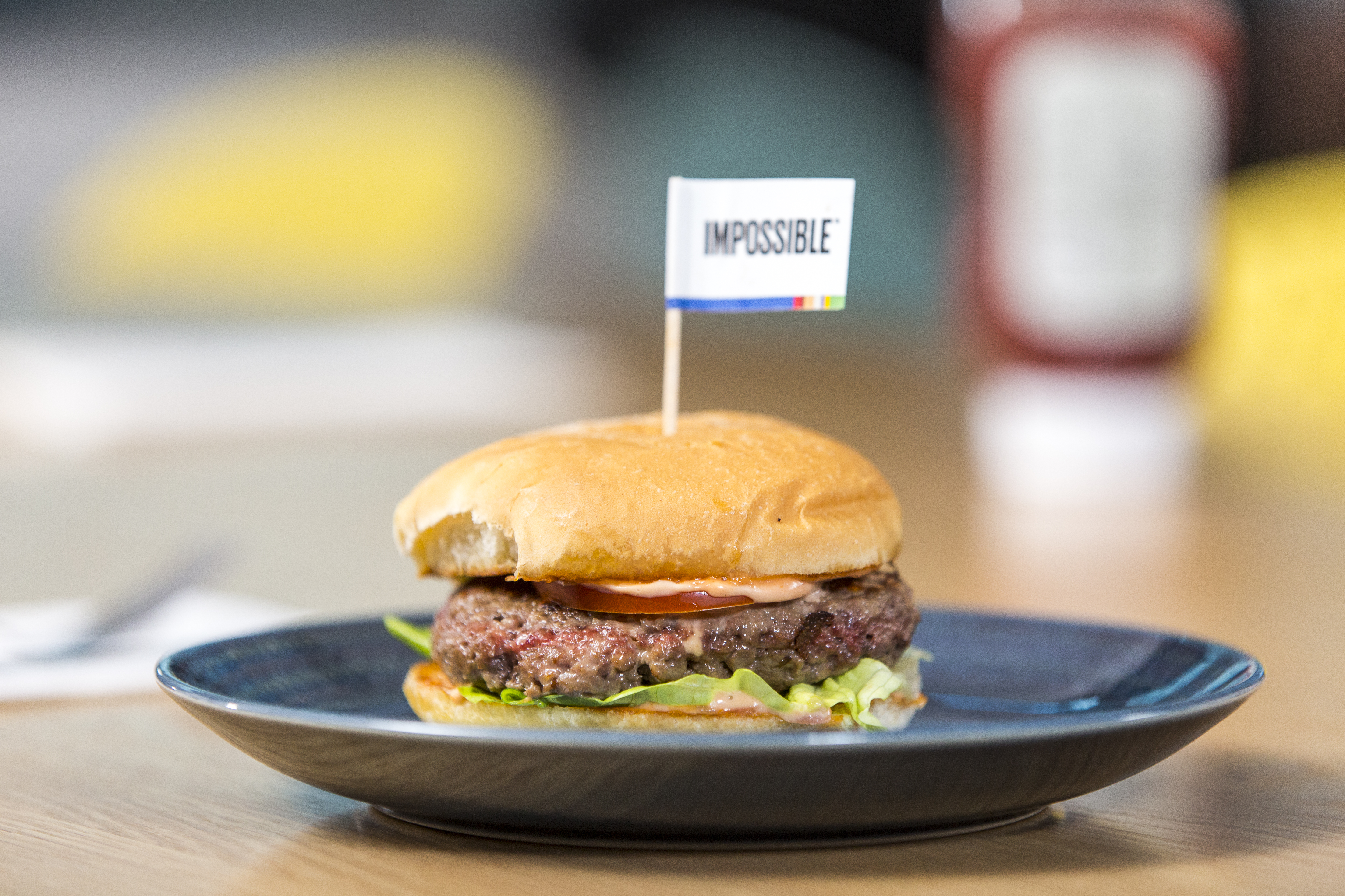 Burger on a plate with an “Impossible” flag in it.