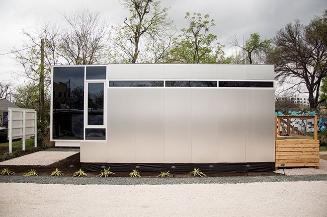 A sleek, small, mobile home with stainless metal siding, tinted windows, and small clerestory windows at the top.