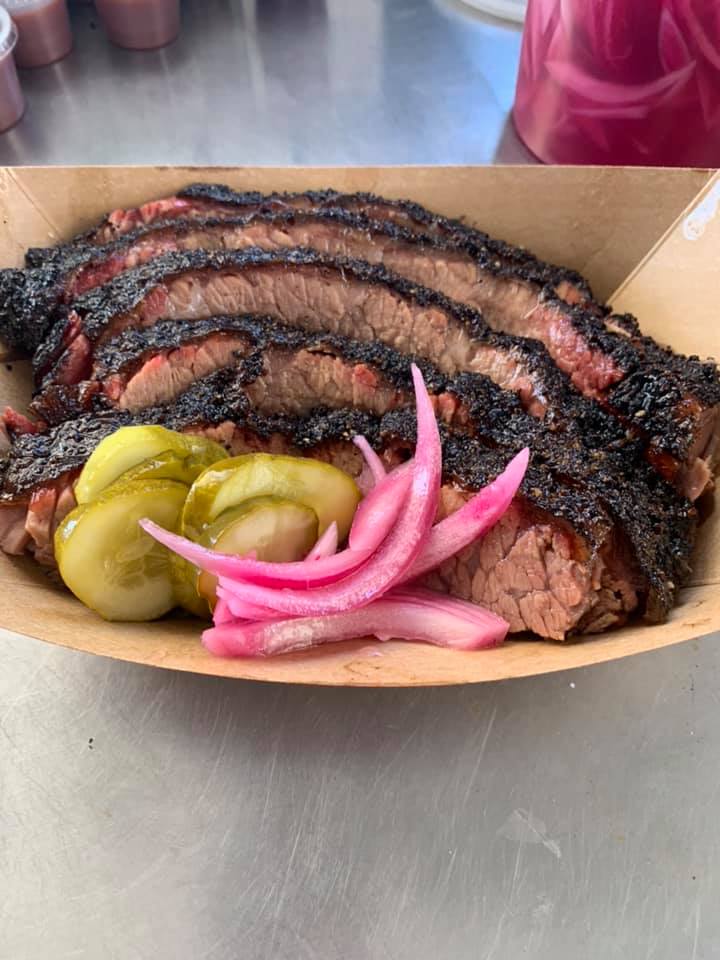 A paper tray of sliced brisket, pickle slices, and onions from Whitfield’s