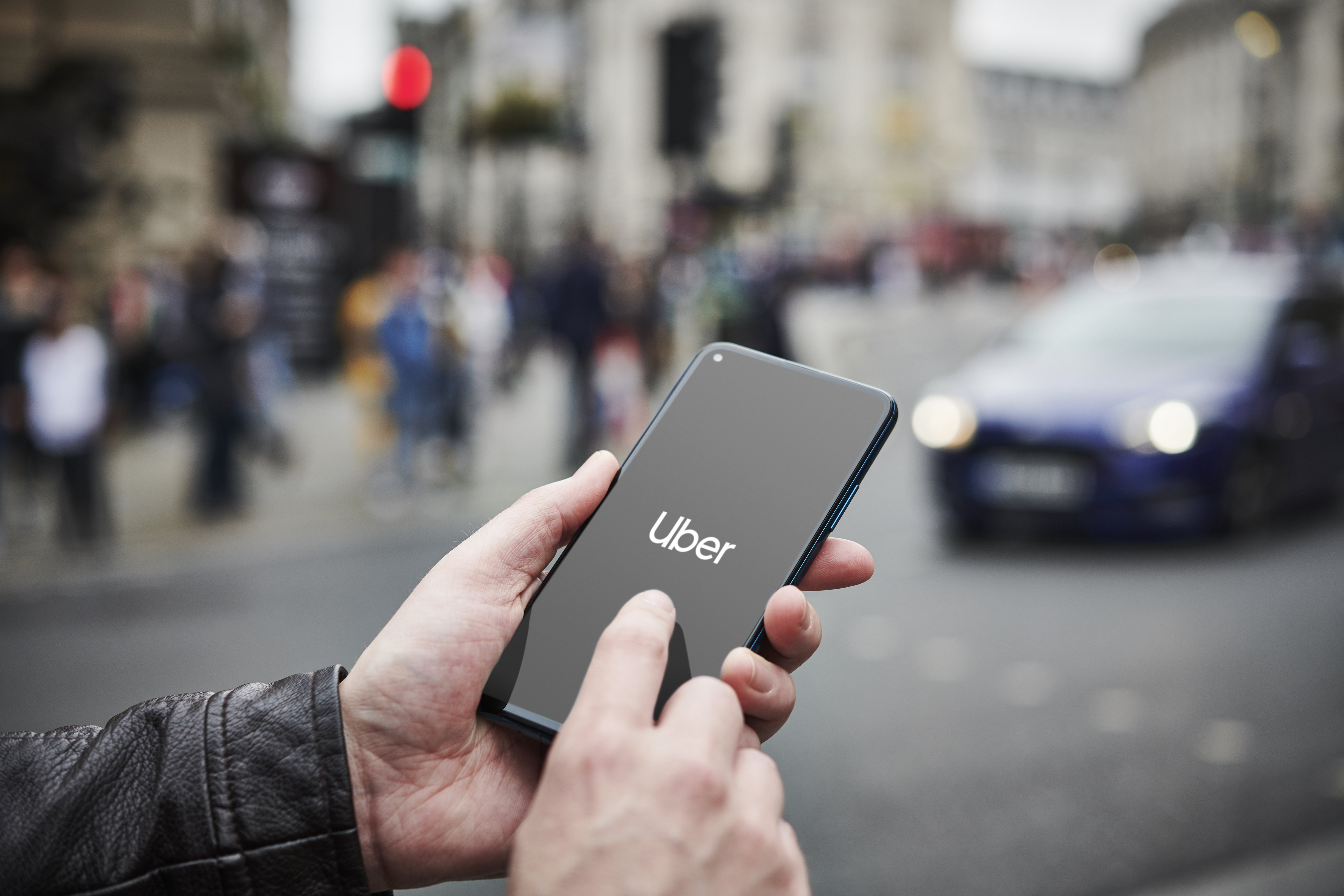 A man holds a cell phone open to the Uber app.