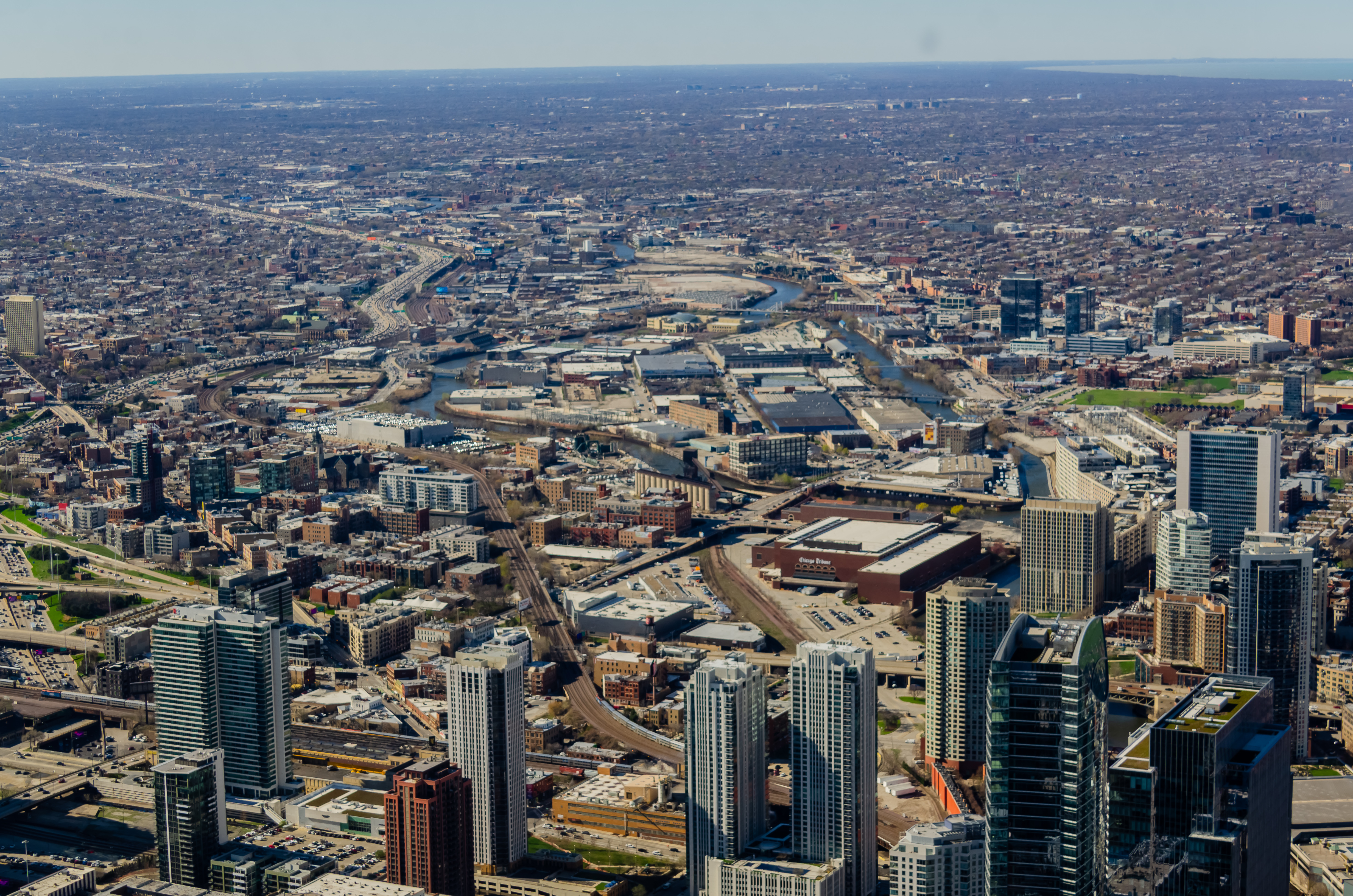A bird’s eye view of Chicago shows the confluence of the river, a few towers on the west end of the Loop, and smaller buildings of neighborhoods.