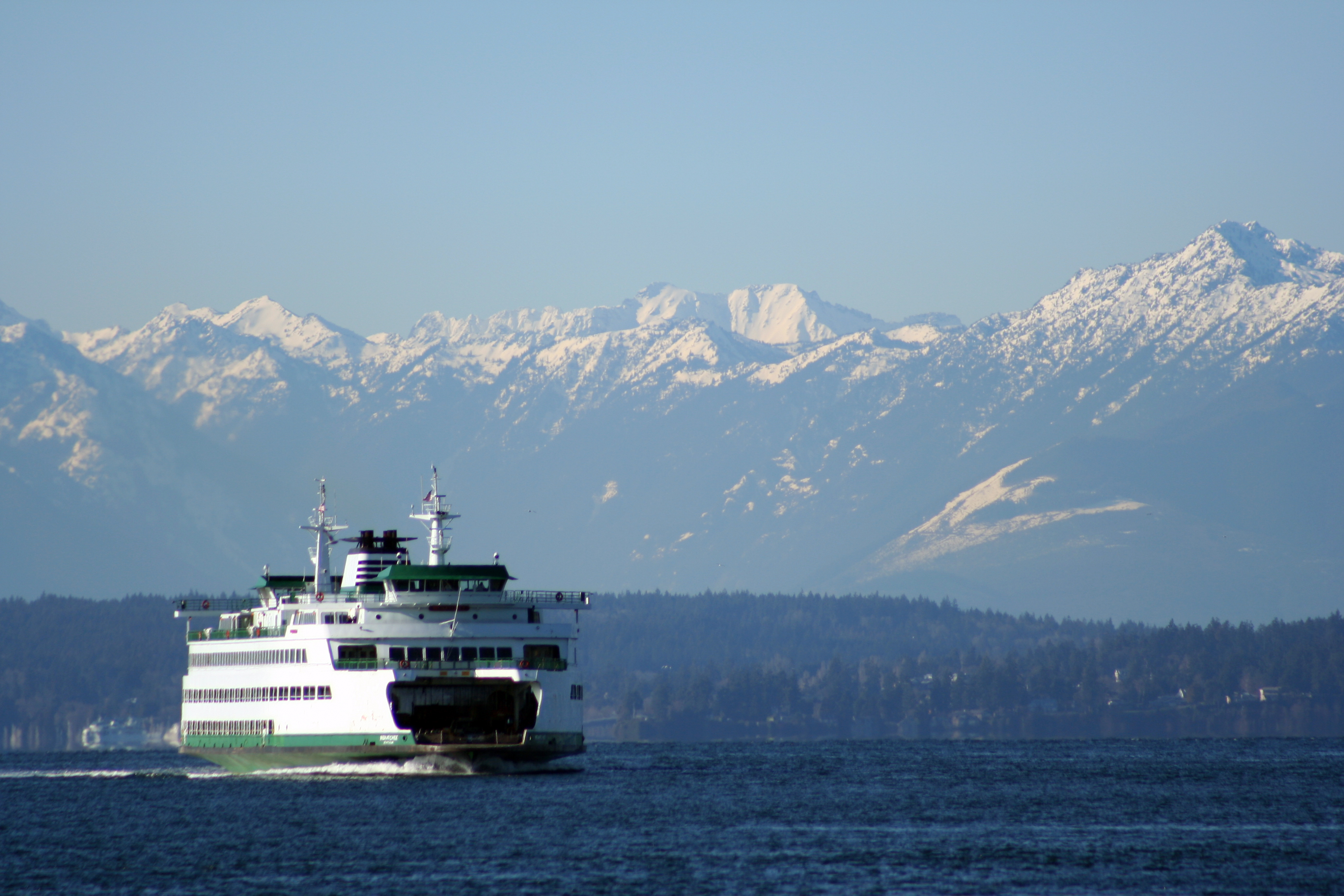 A ferry operating on open water with mountains in the background.