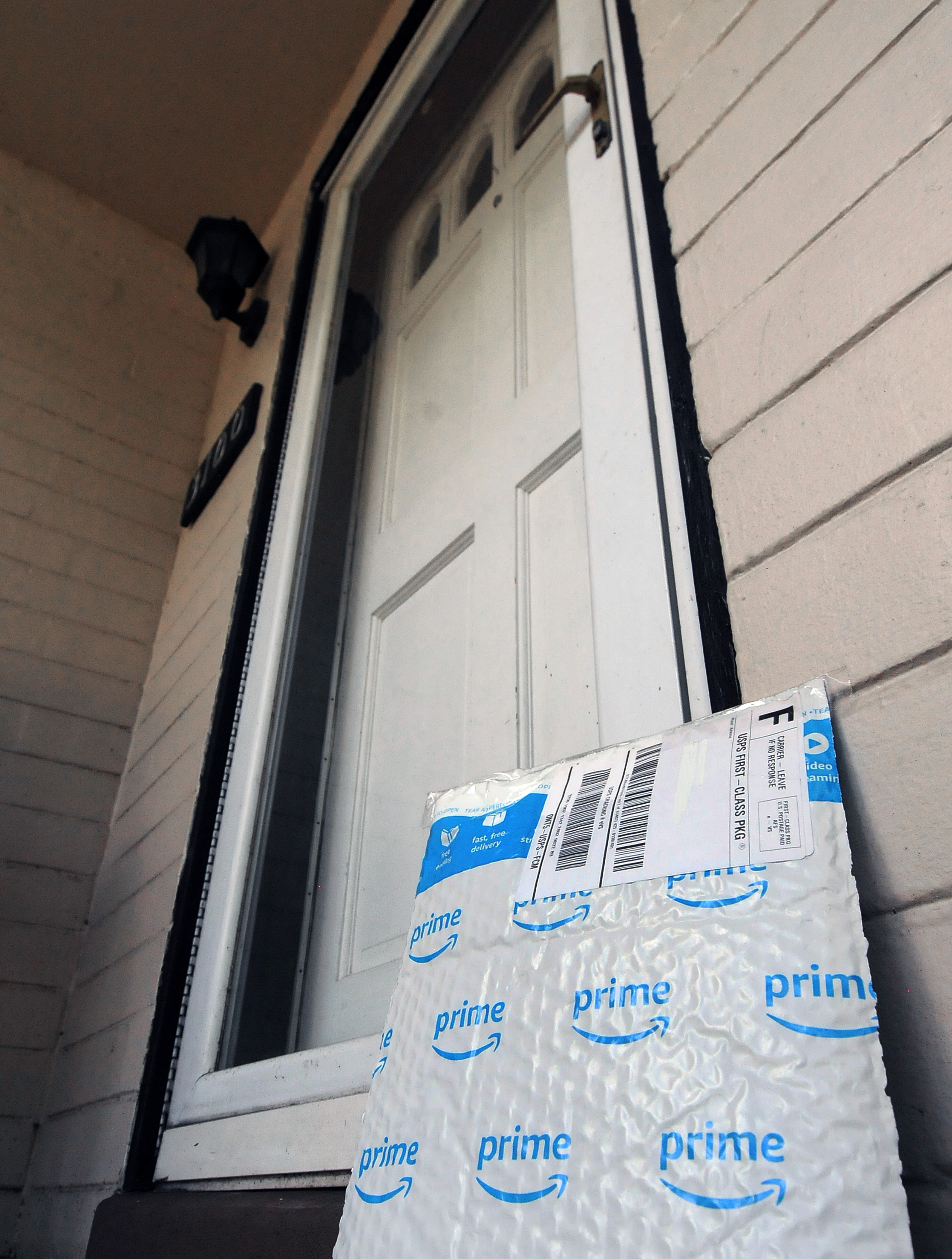 An Amazon Prime padded envelope leans against the exterior of a front door.
