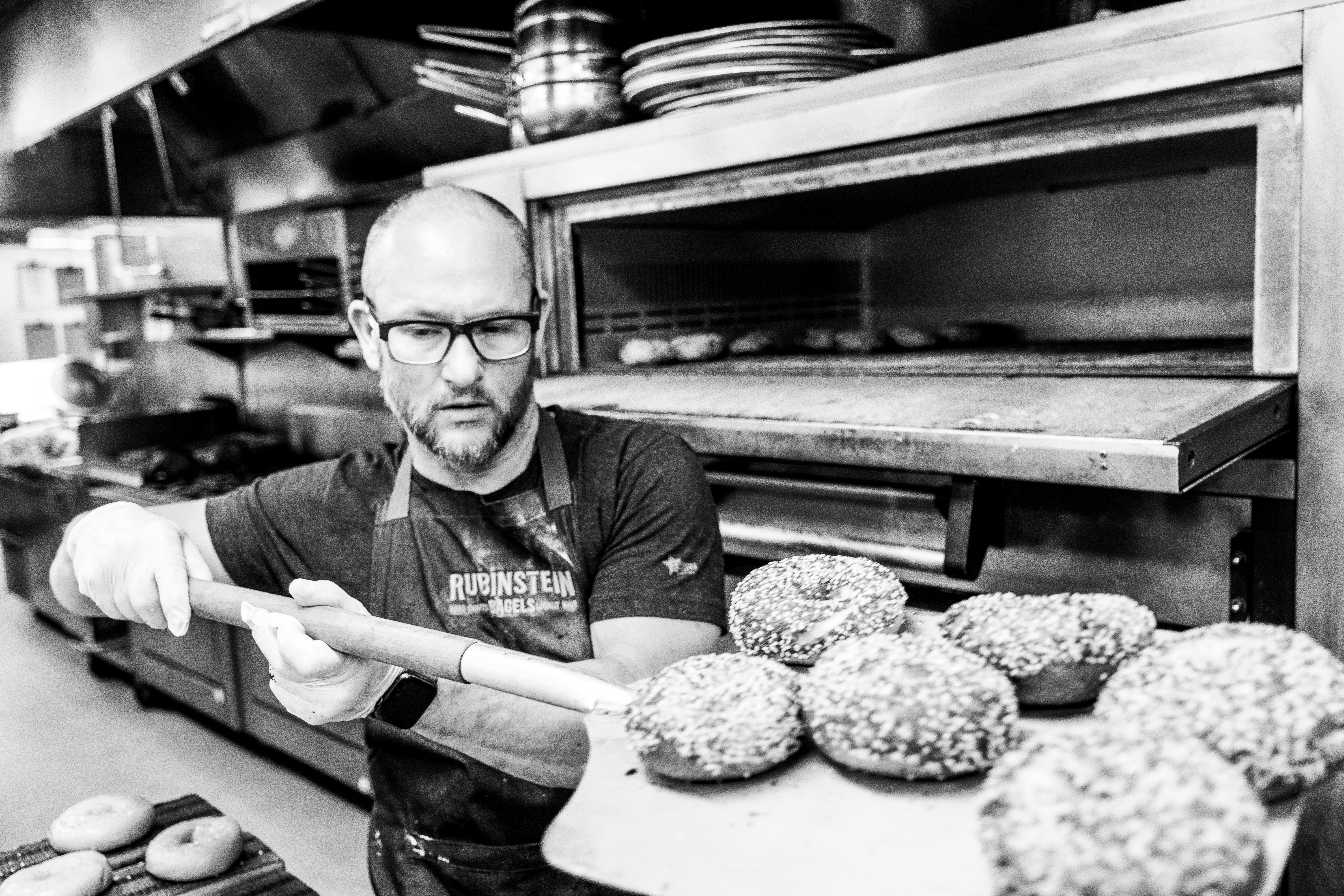 Bagel maker Andrew Rubinstein taking bagels out of the oven