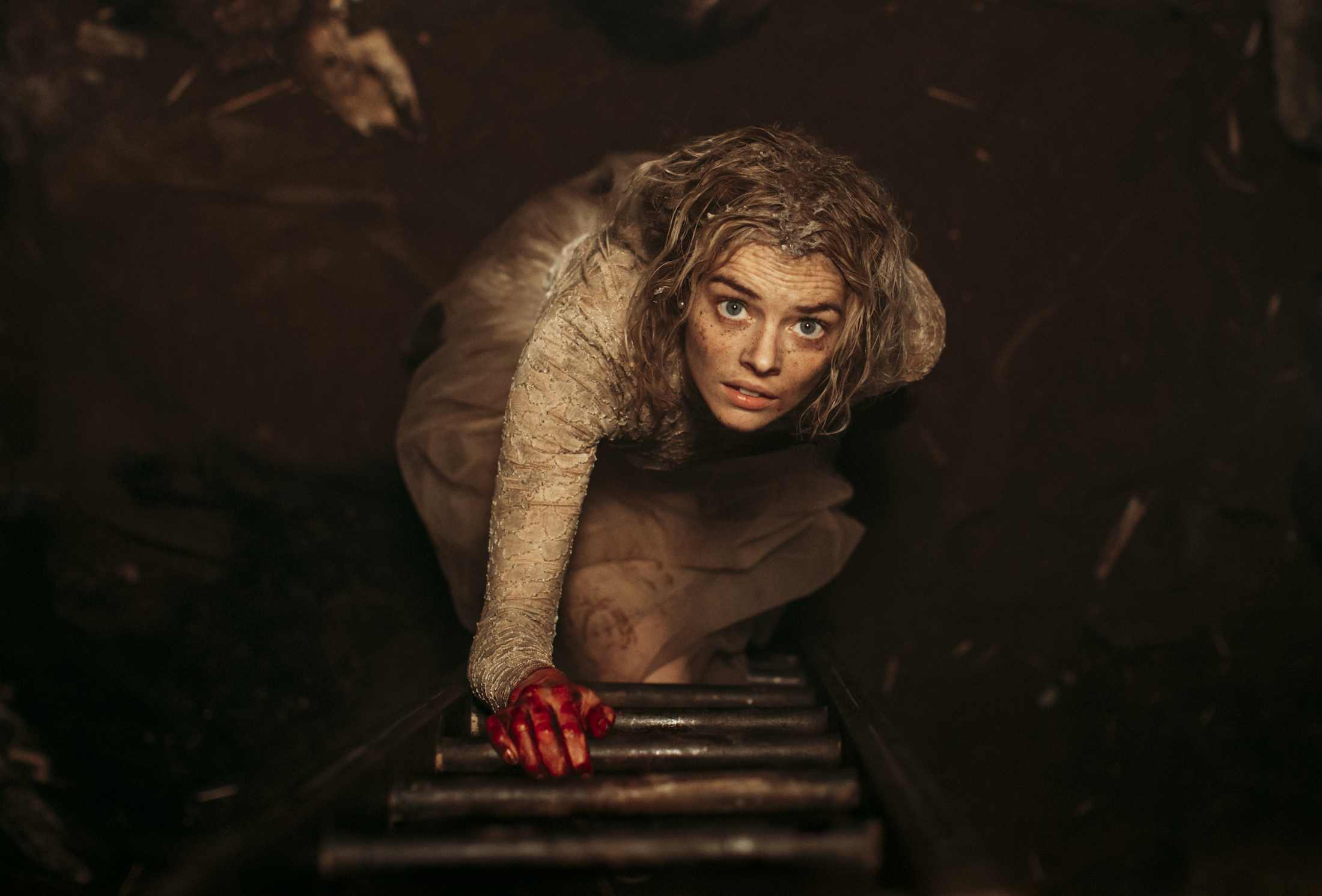 Grace (Samara Weaving) looks up a ladder, holding the first rung with her bloody hand in a shot from Ready or Not
