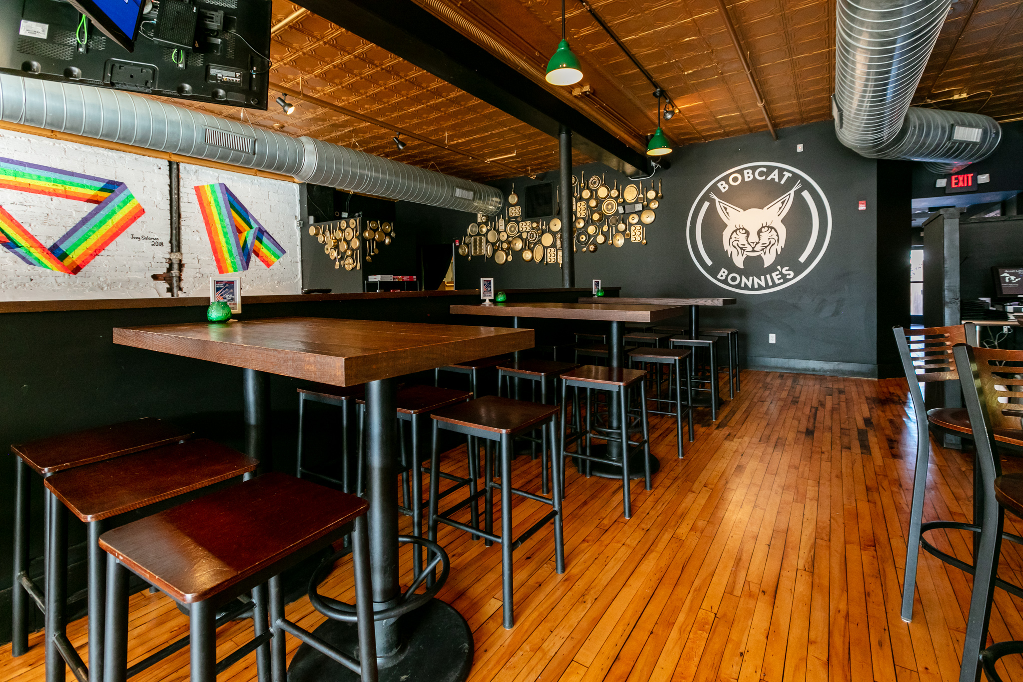 Rainbow strips are painted on a white wall with a Bobcat Bonnie’s logo painted in black and white nearby at the Ferndale restaurant’s dining room.