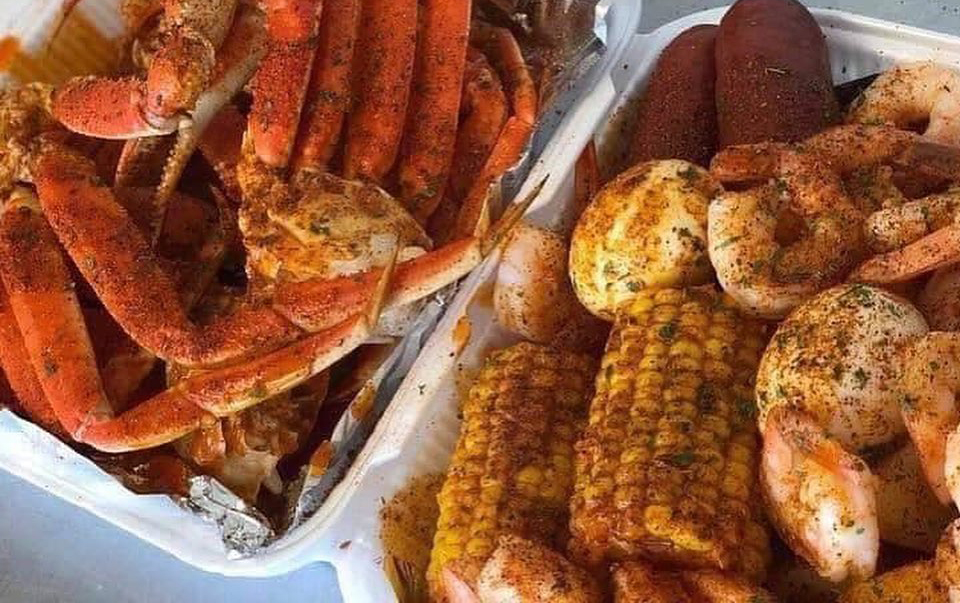 A plate of snow crab legs, with sides of shrimp, sausage, potatoes and corn on the cob.
