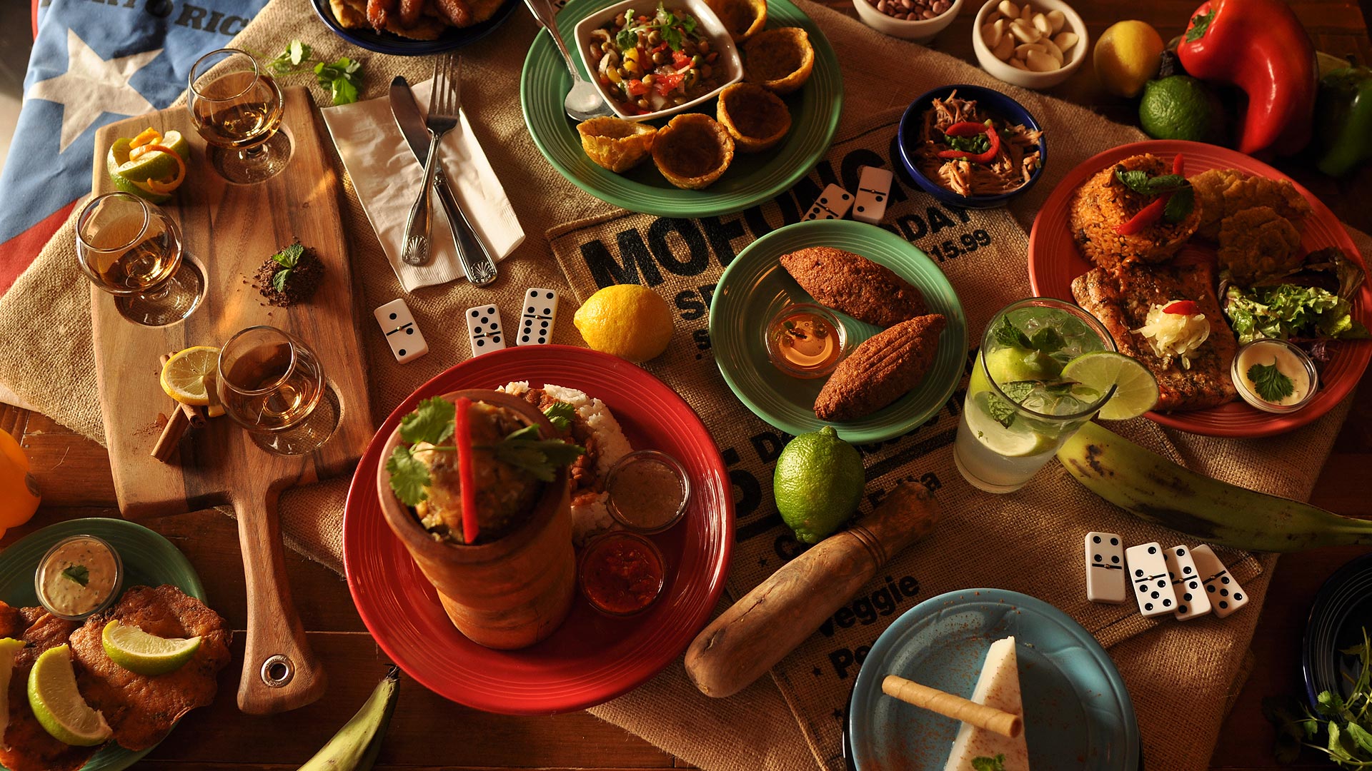 A bird’s eye view showing a canvas-covered table with a variety of colorful plates, food, and cocktails.