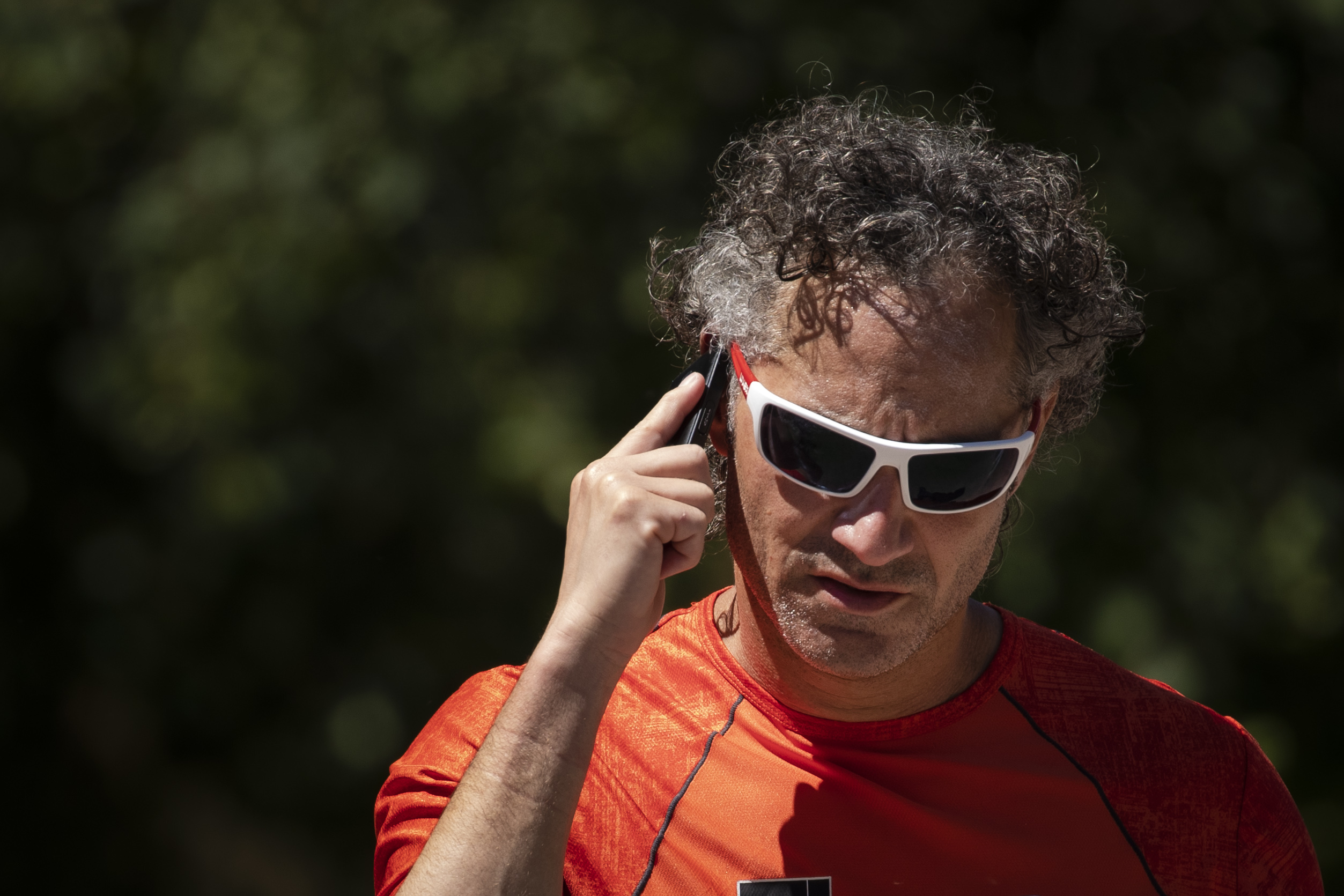 A candid shot of Palantir CEO Alex Karp wearing sunglasses and talking on his cell phone.