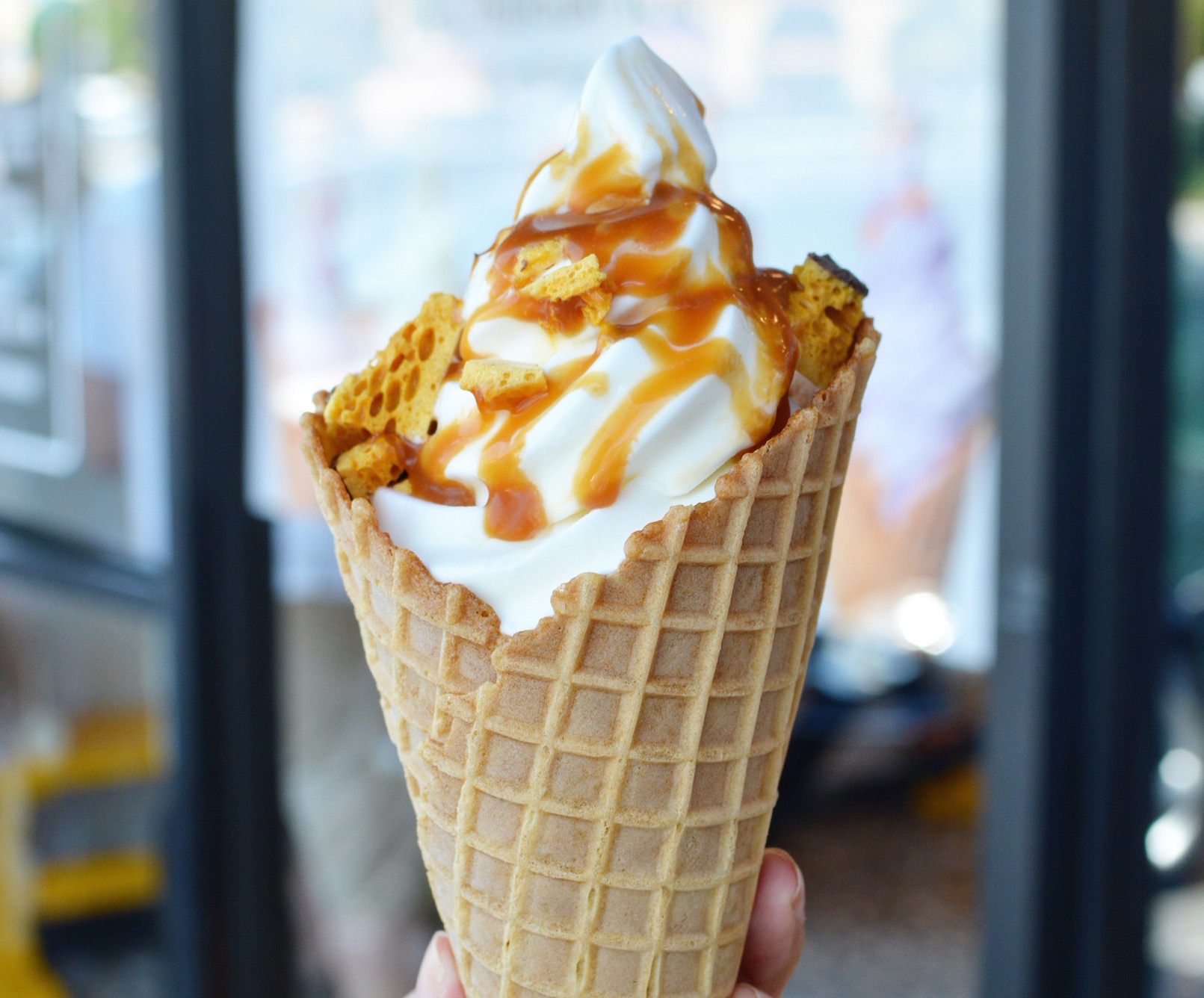A soft serve ice cream inside a cone with a drizzle of caramel