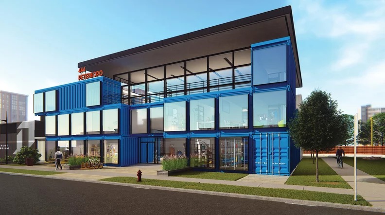 A blue building made of shipping containers with square windows and a metallic awning.