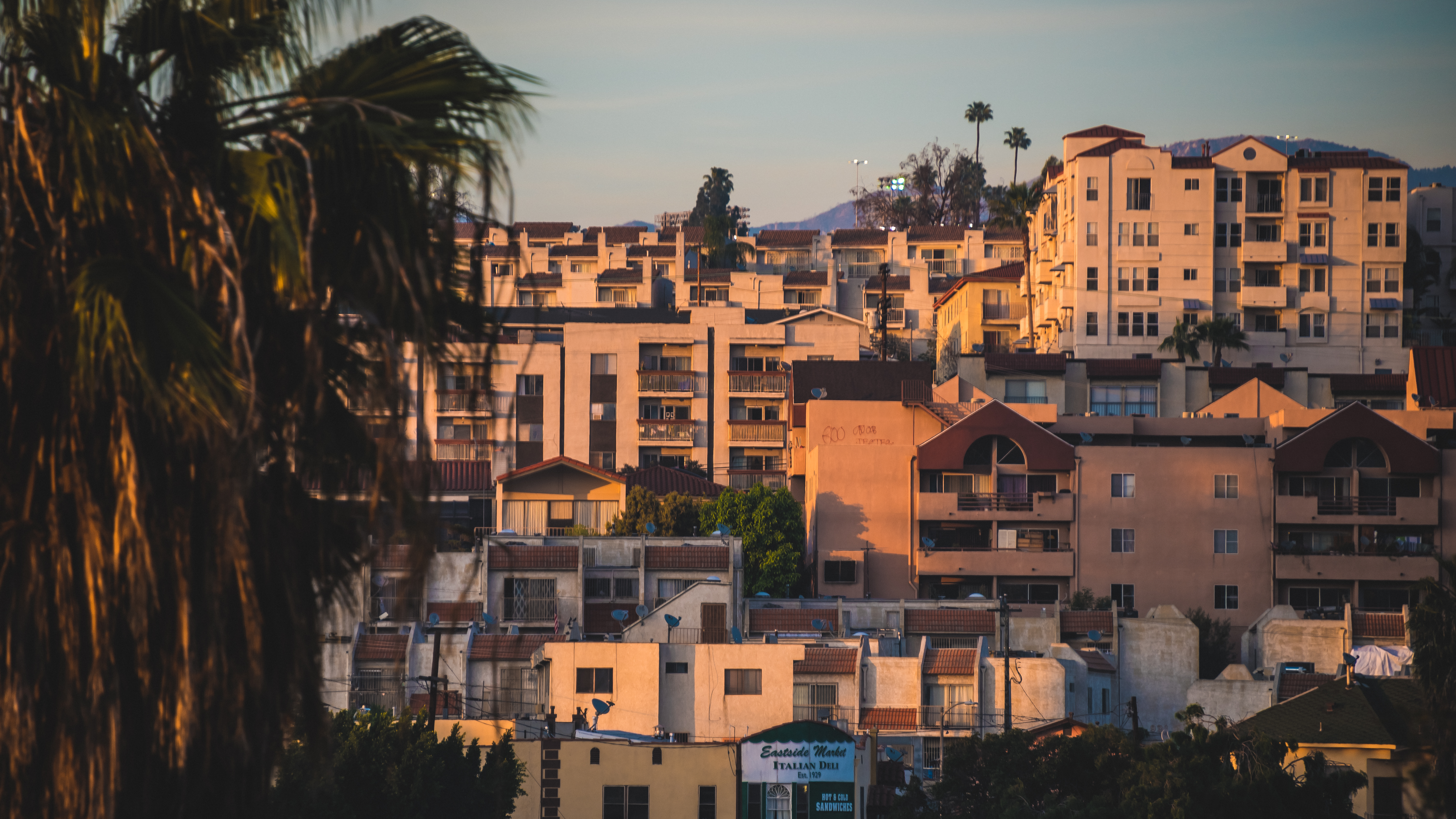 A cluster of dense white and beige apartments on a hillside at sunset.