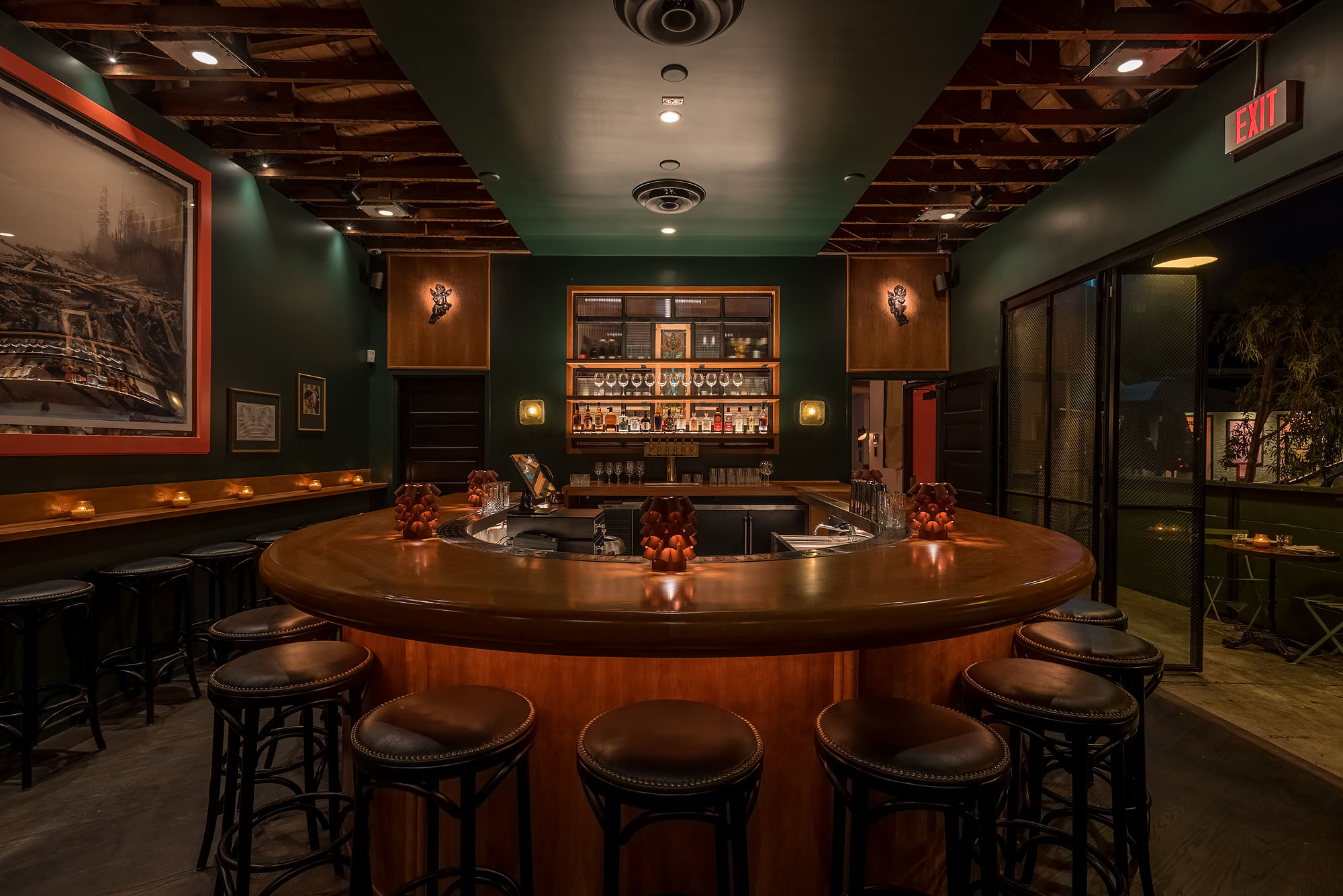 A rounded bar looks out over dark green walls and a glowing back bar.