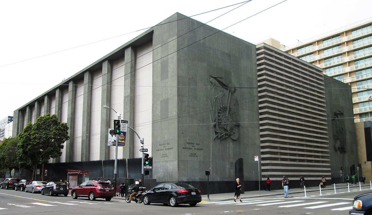A massive corner substation building, a low, gray cement building behind a black fence.