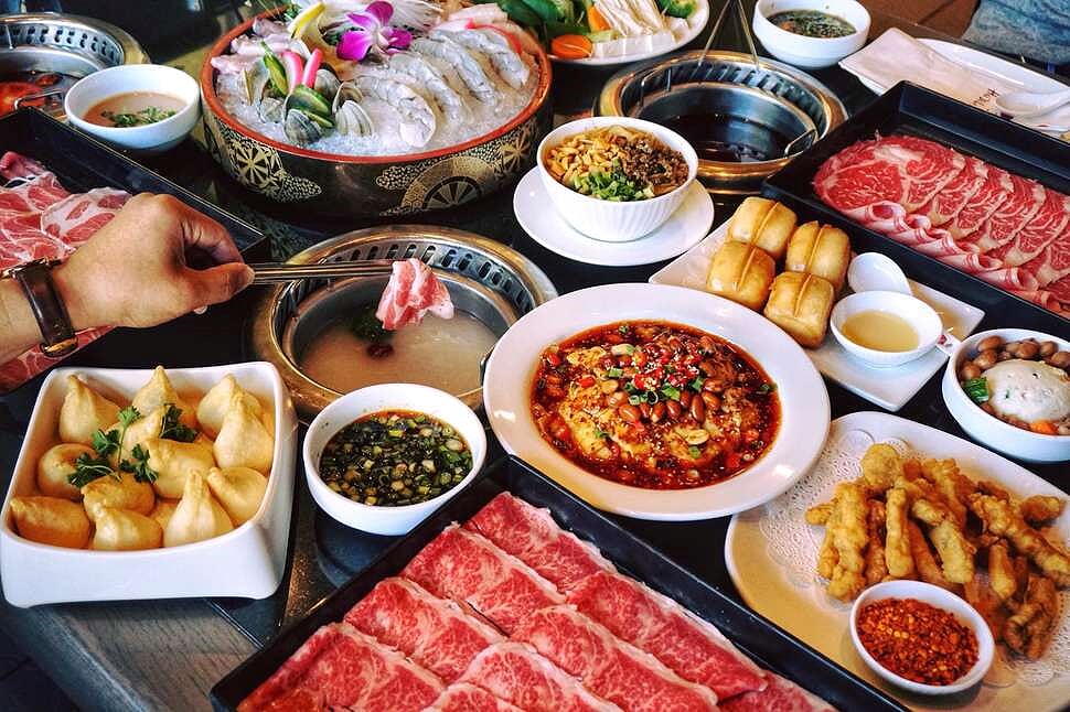 A top-down view of a table full of dishes at Hai Di Lao, including hot pot