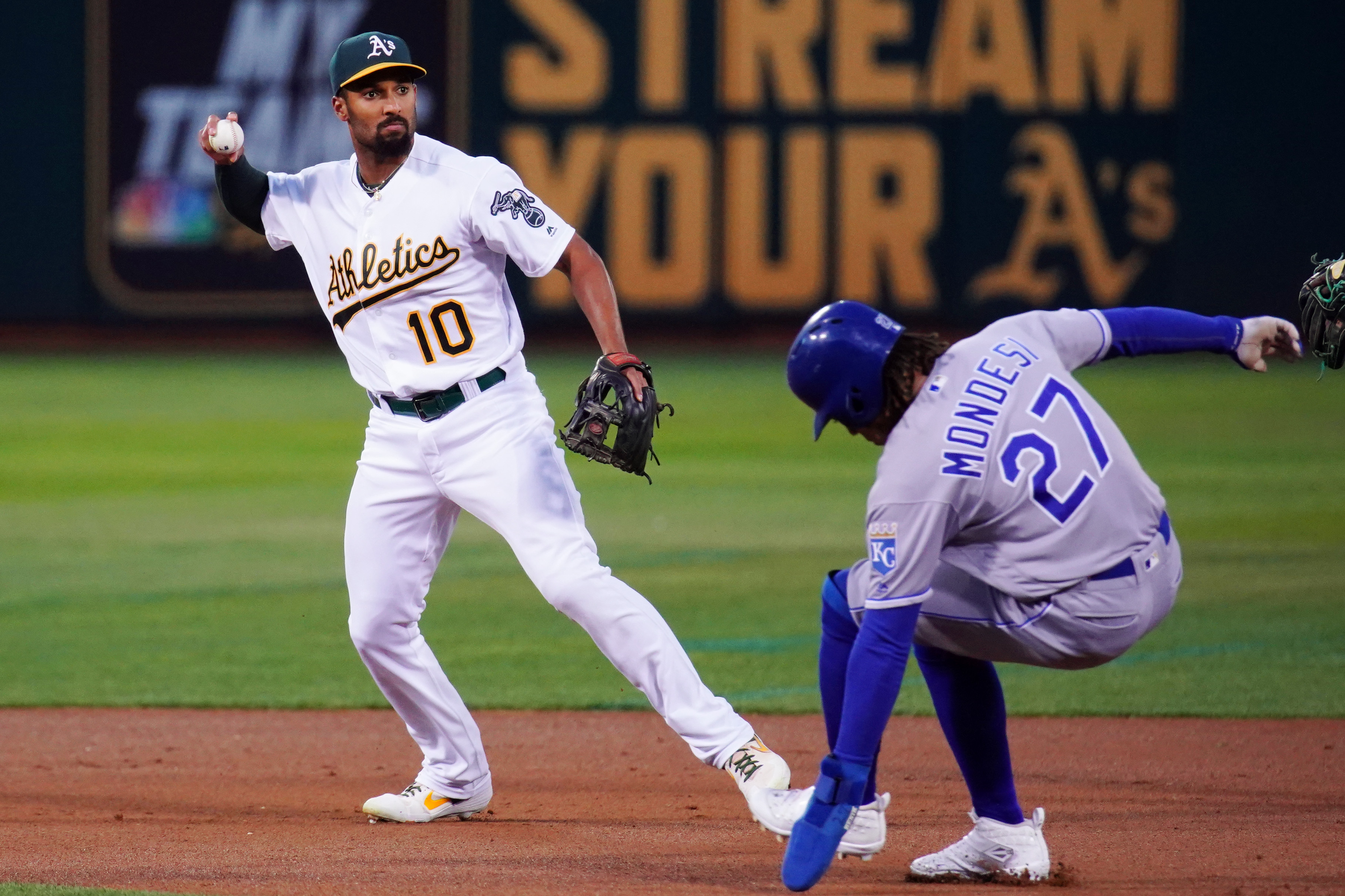 Marcus Semien #10 of the Oakland Athletics turns a double play over Adalberto Mondesi #27 of the Kansas City Royals during the first inning at Ring Central Coliseum on September 17, 2019 in Oakland, California.