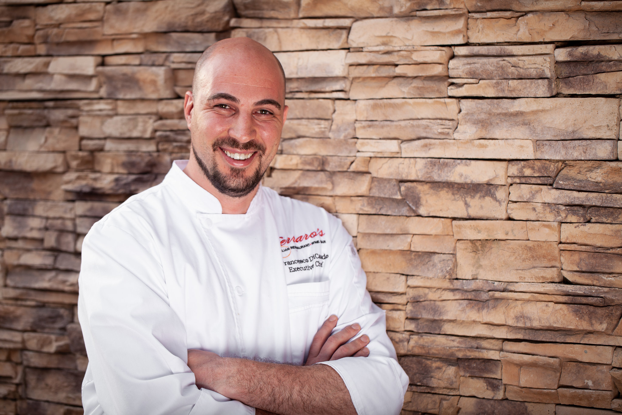 A chef wearing a white coat with his arms crossed