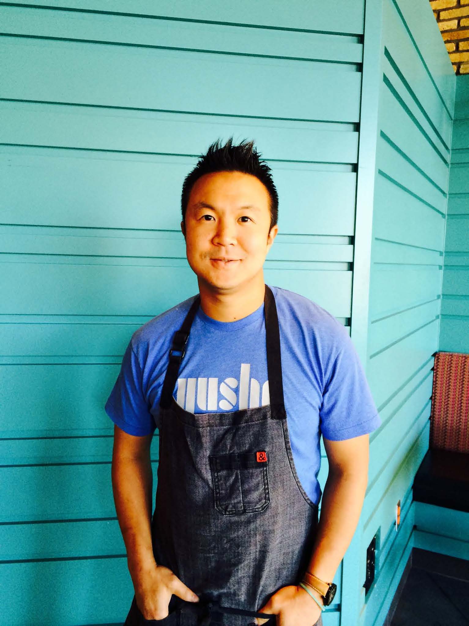 A chef wears a blue T-shirt and a black apron