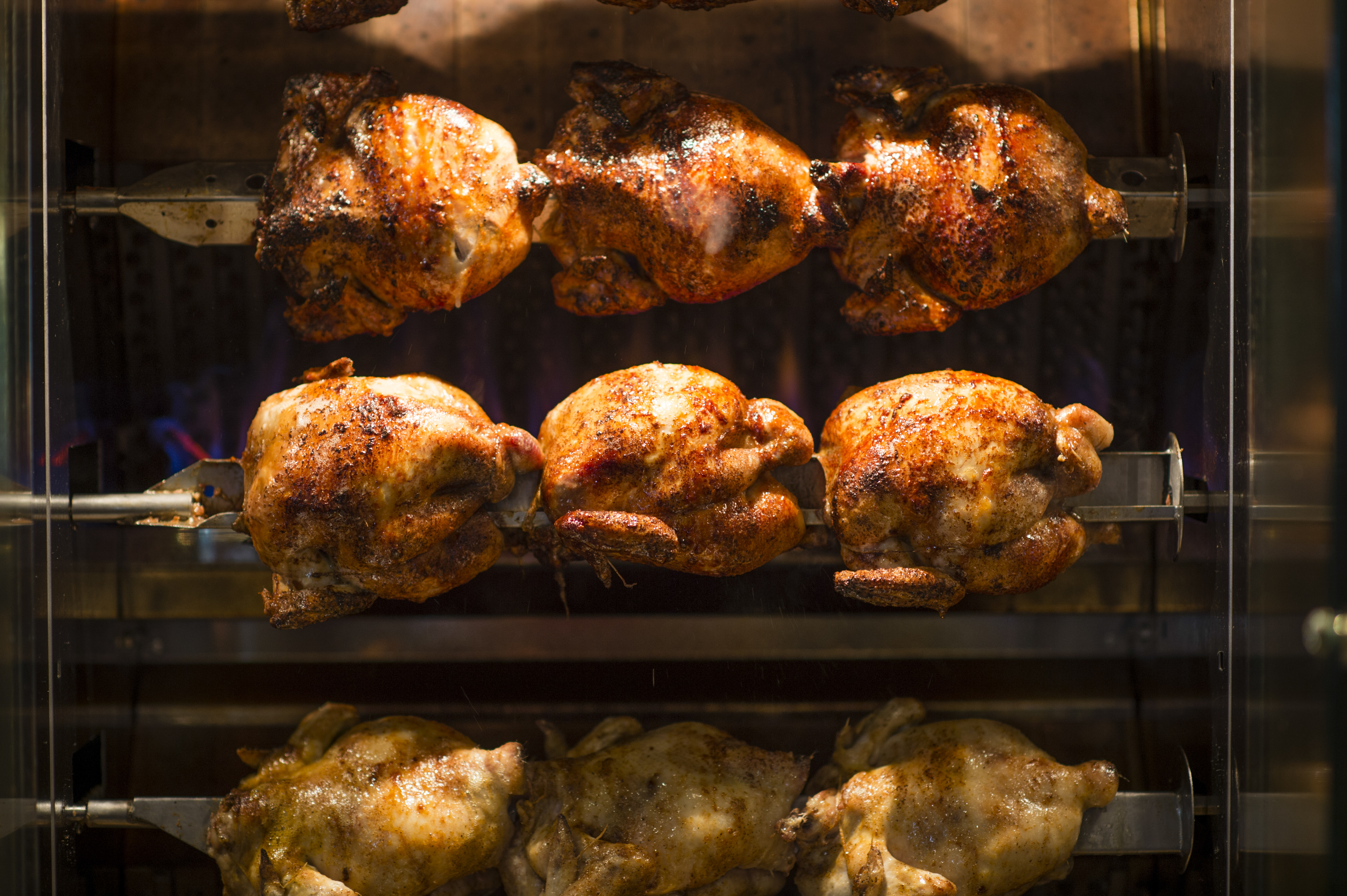 A close-up photo of nine rotisserie chickens roasting at Chicken on the Hill