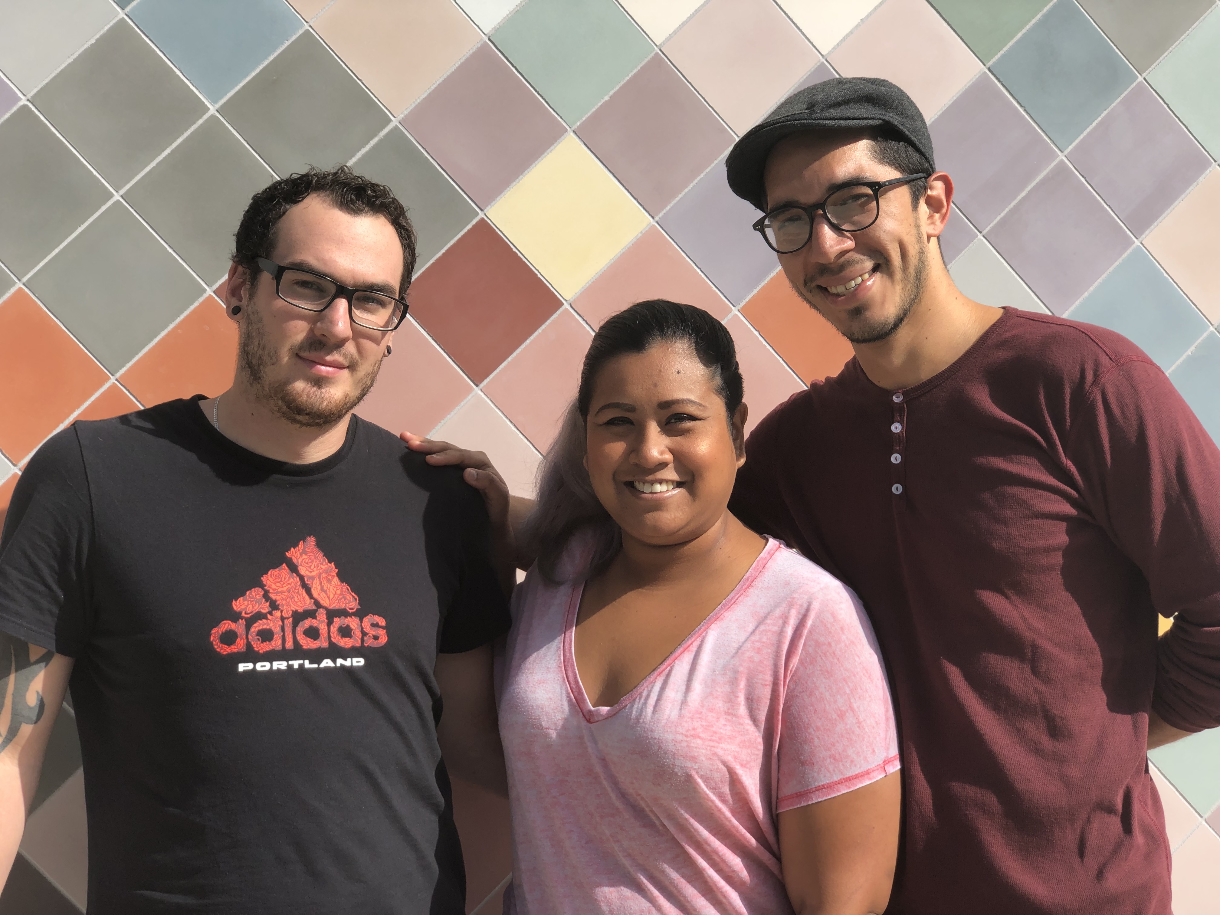A picture of three people standing in front of a colorful wall at Mestizo