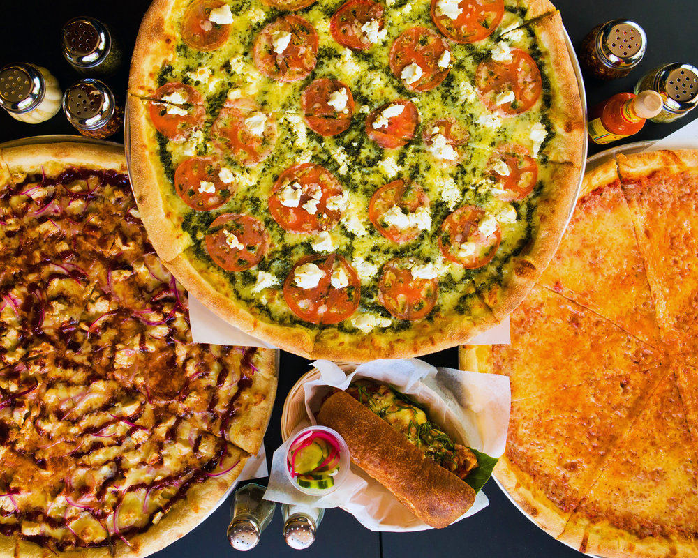 Three pizzas with various toppings are staggered on a table