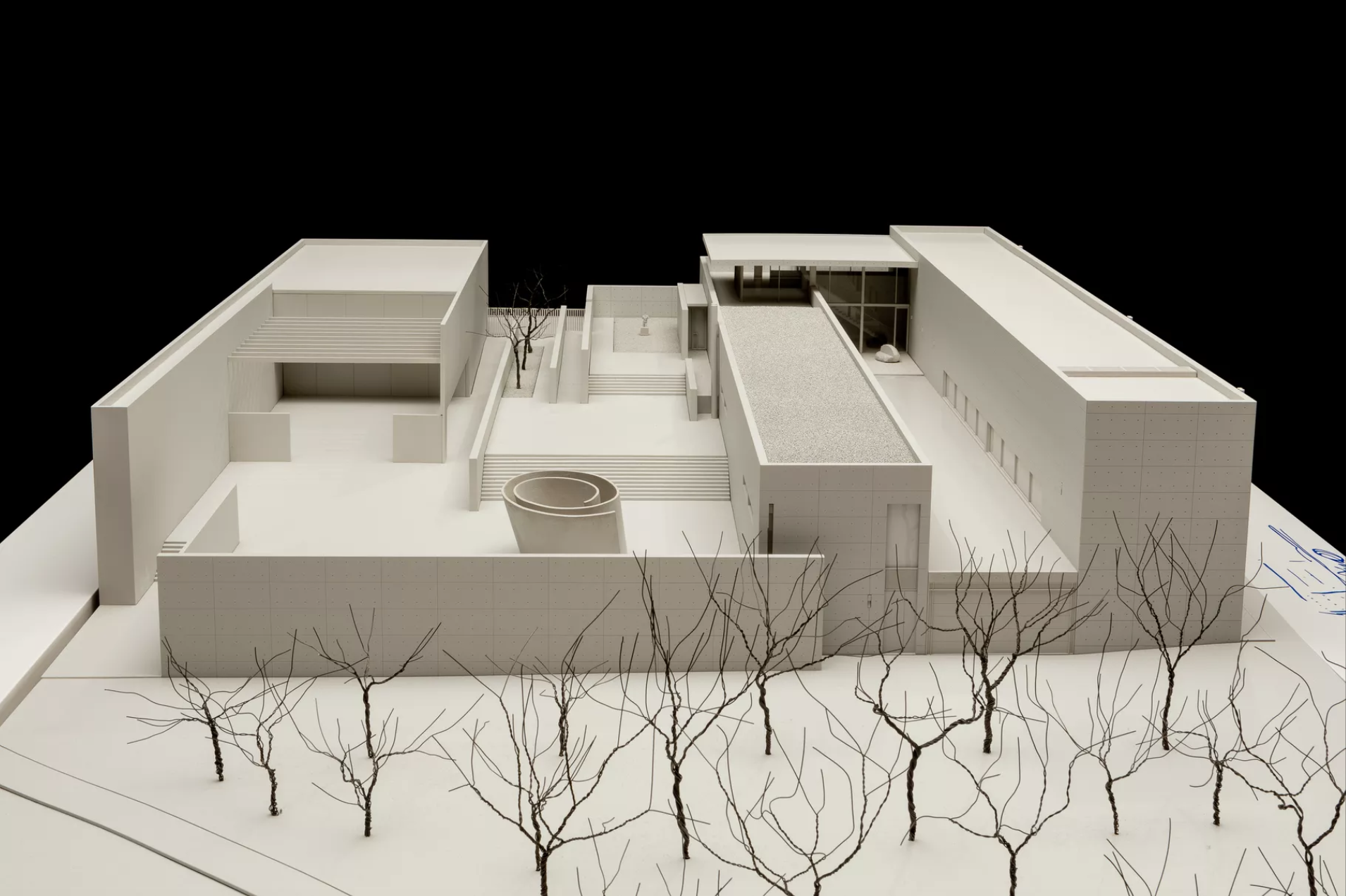 A scale model of a rectangular building with a multilevel roof and cut-outs, creating interior courtyards. 