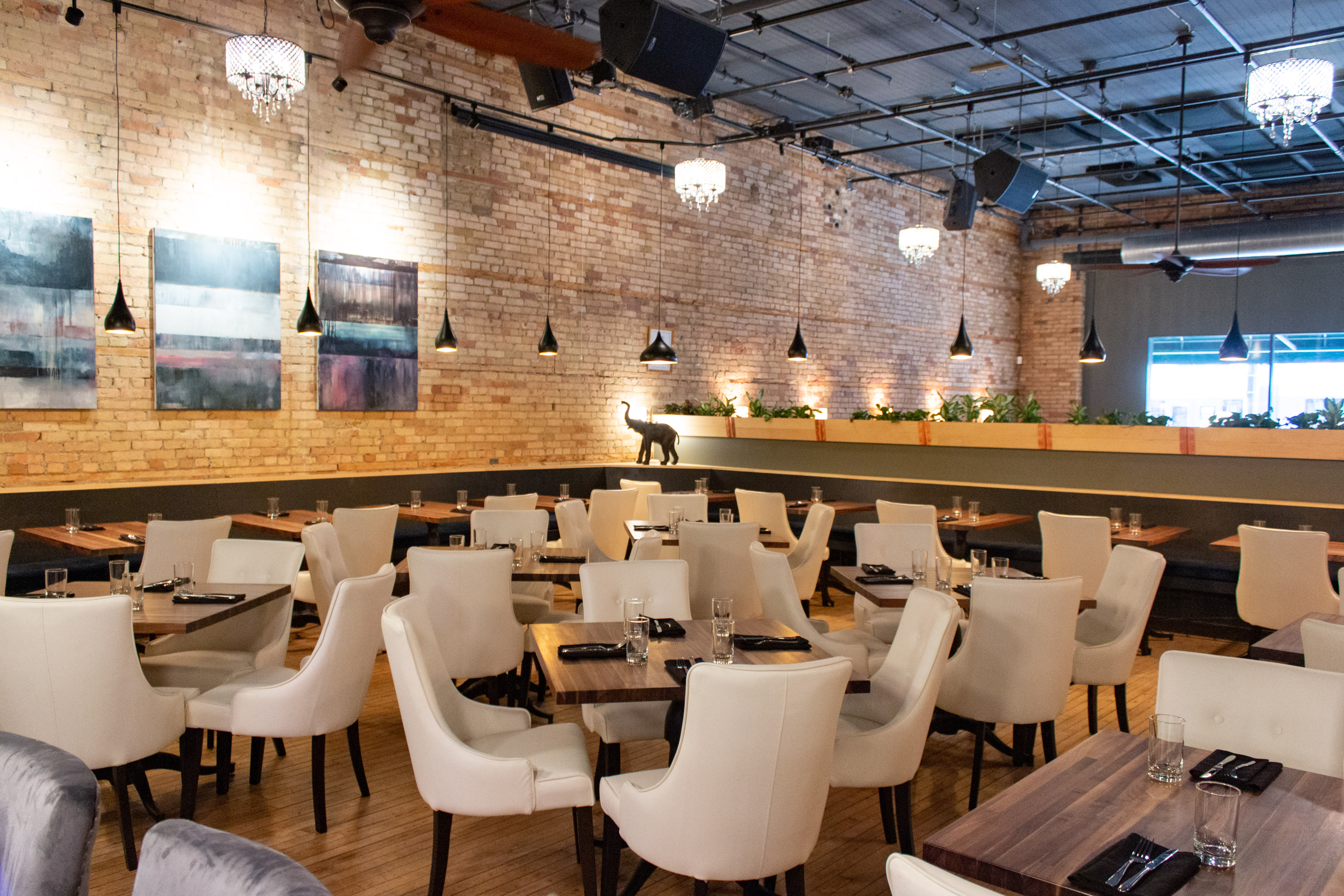 The yellow-lit dining room with brick walls and white chairs with wood tables.