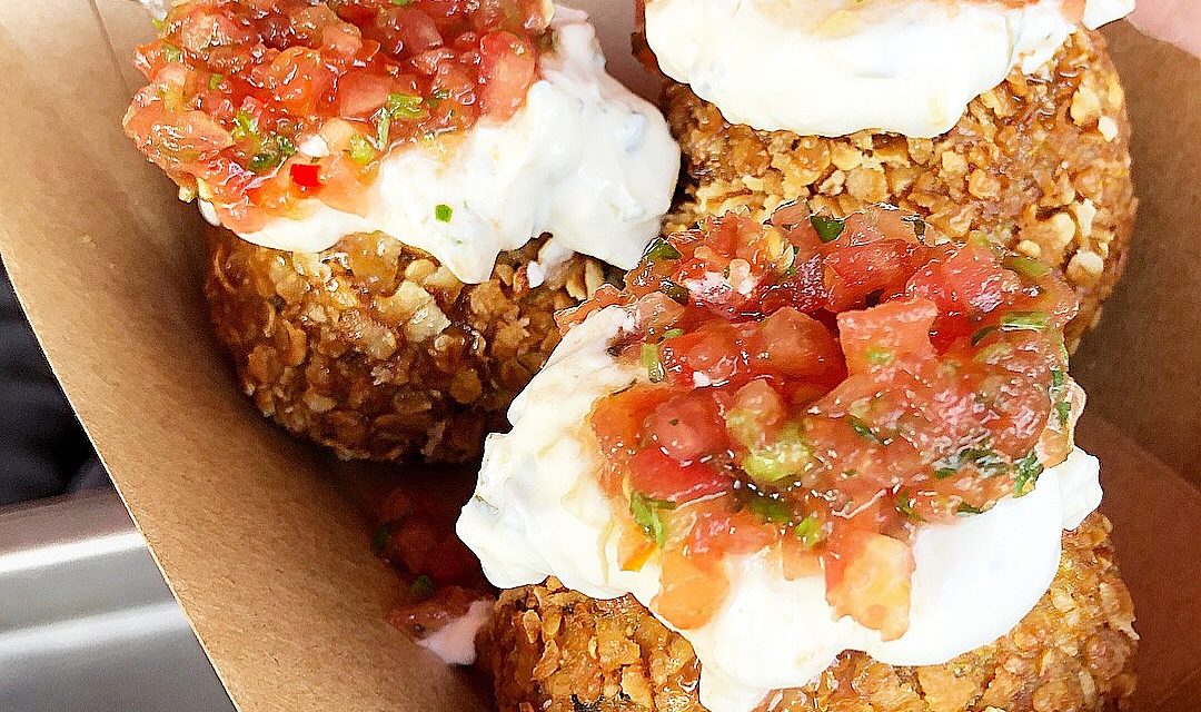 Close-up of quinoa balls topped with cream and chopped tomatoes