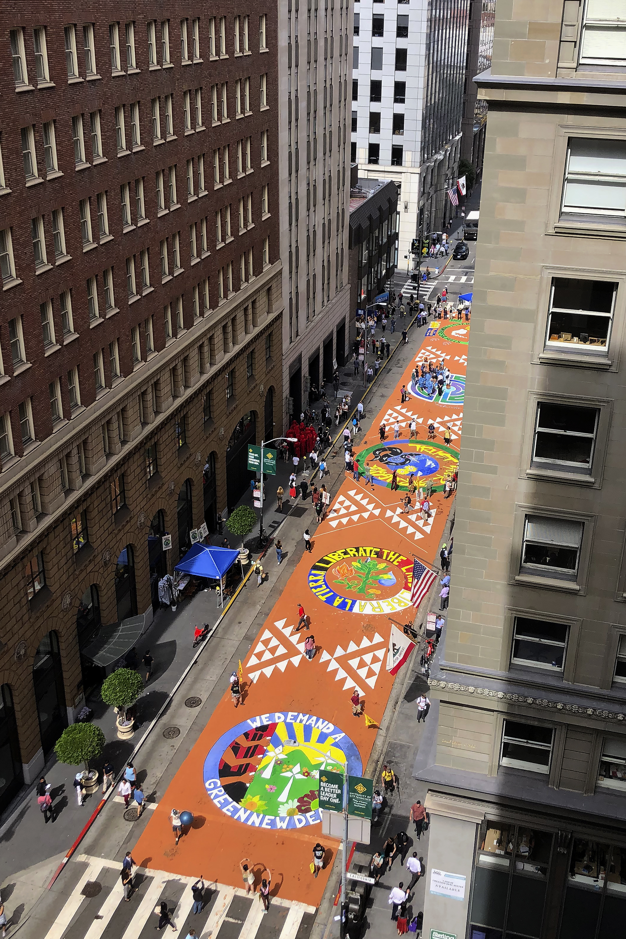 Block-long mural on pavement as seen from an office building on street.