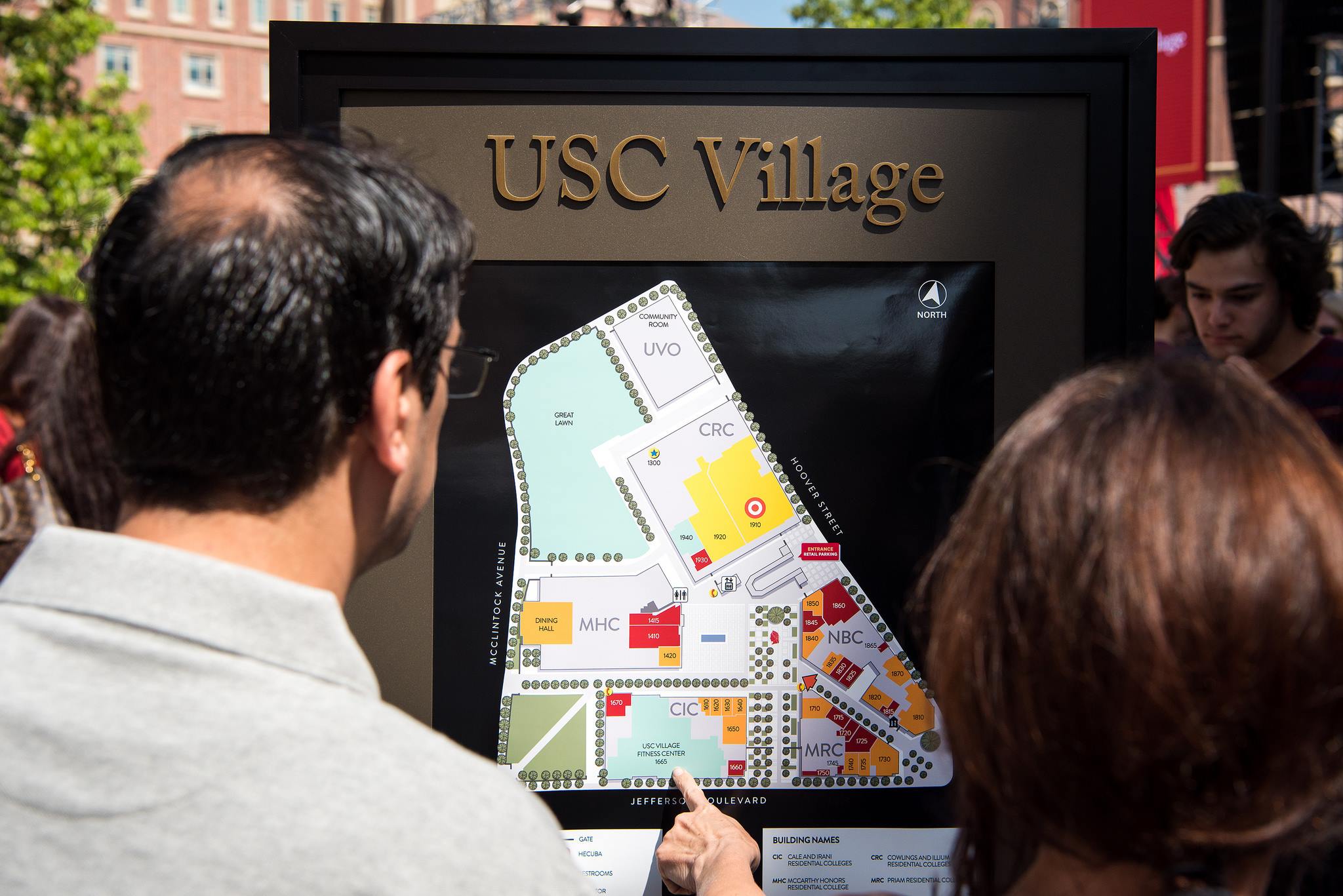 Onlookers point at a map at USC Village.