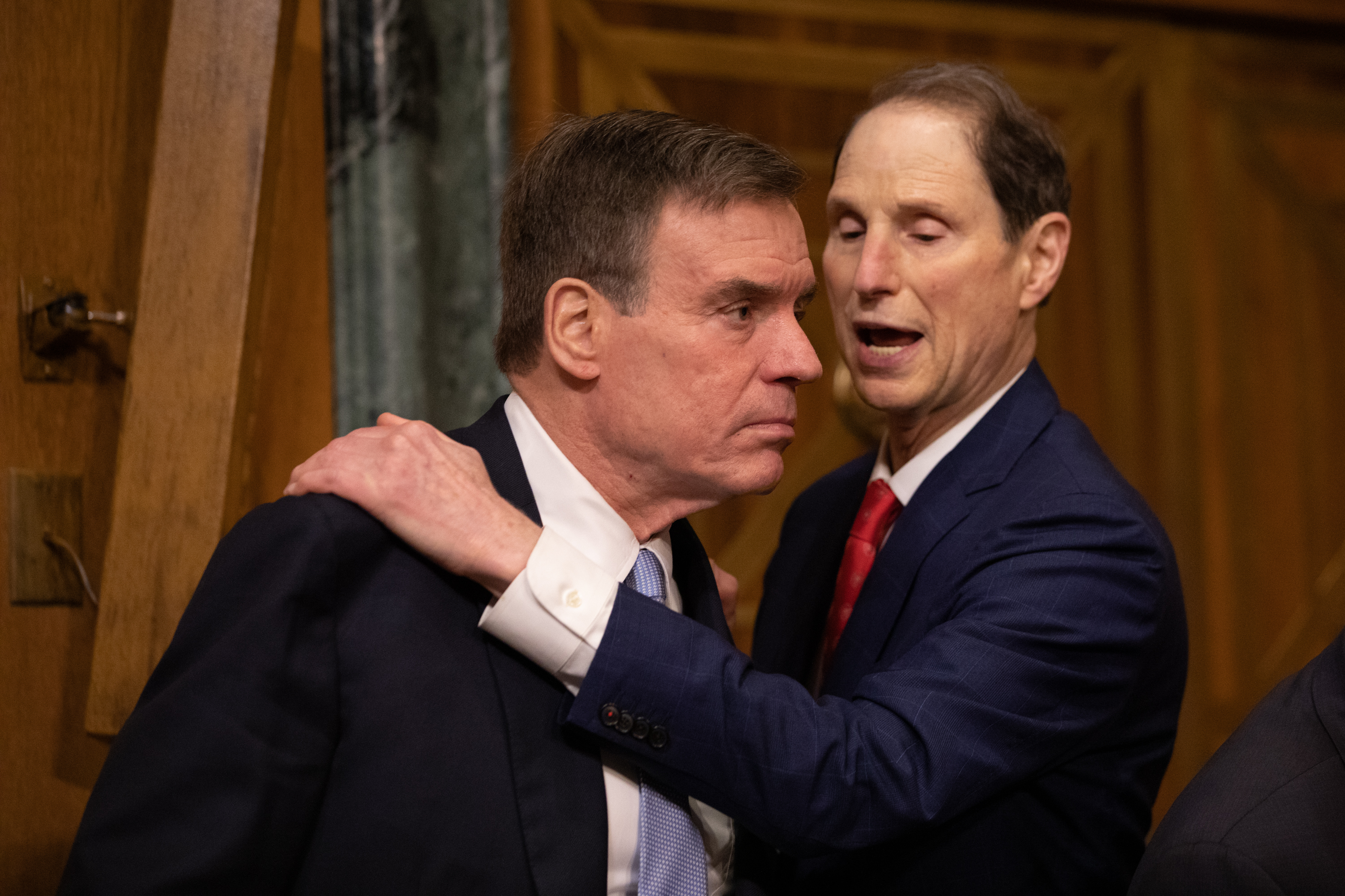 US Senators Ron Wyden and Mark Warner standing close to one another and speaking.
