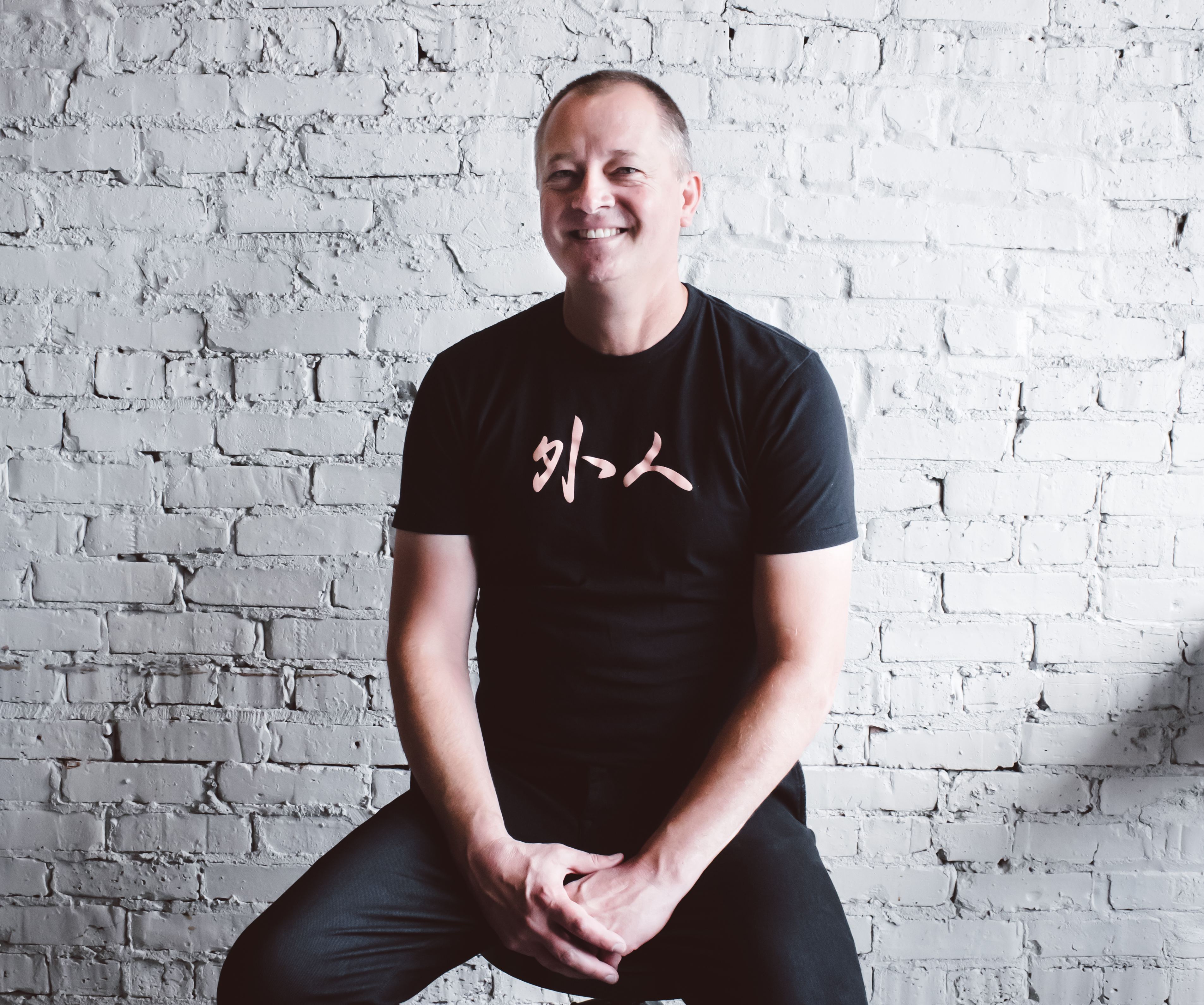 A portrait of a chef wearing a black T-shirt and jeans.