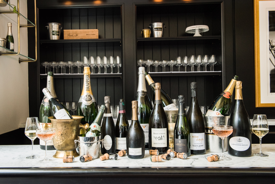 Champagne bottles and glasses of the wine sit on a bar