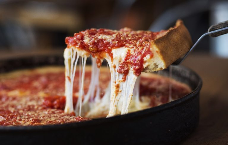 A slice of deep dish pizza is pulled from the pie.