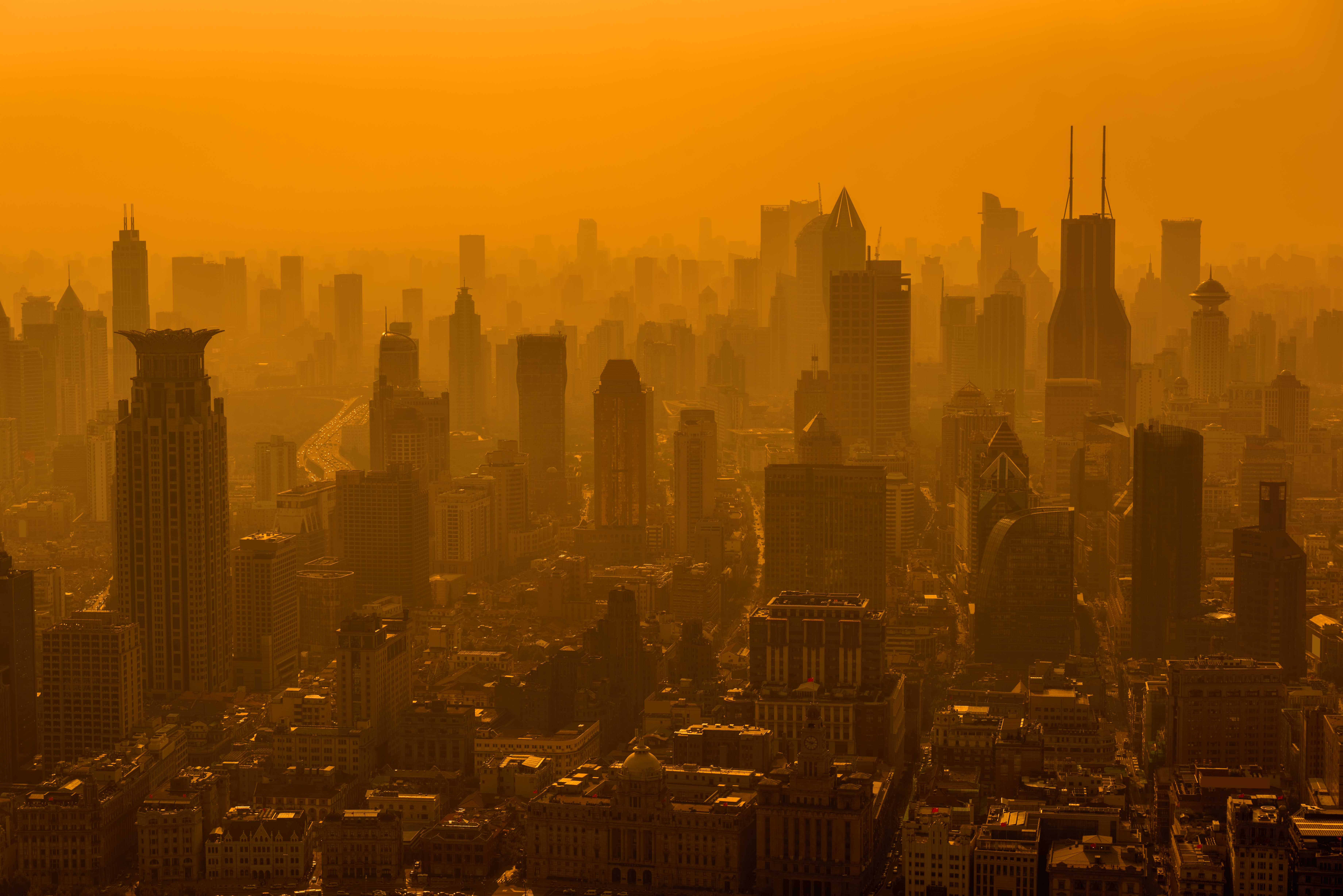The skyline of a modern city seen through an orangish-brown sky, the result of high levels of air pollution.