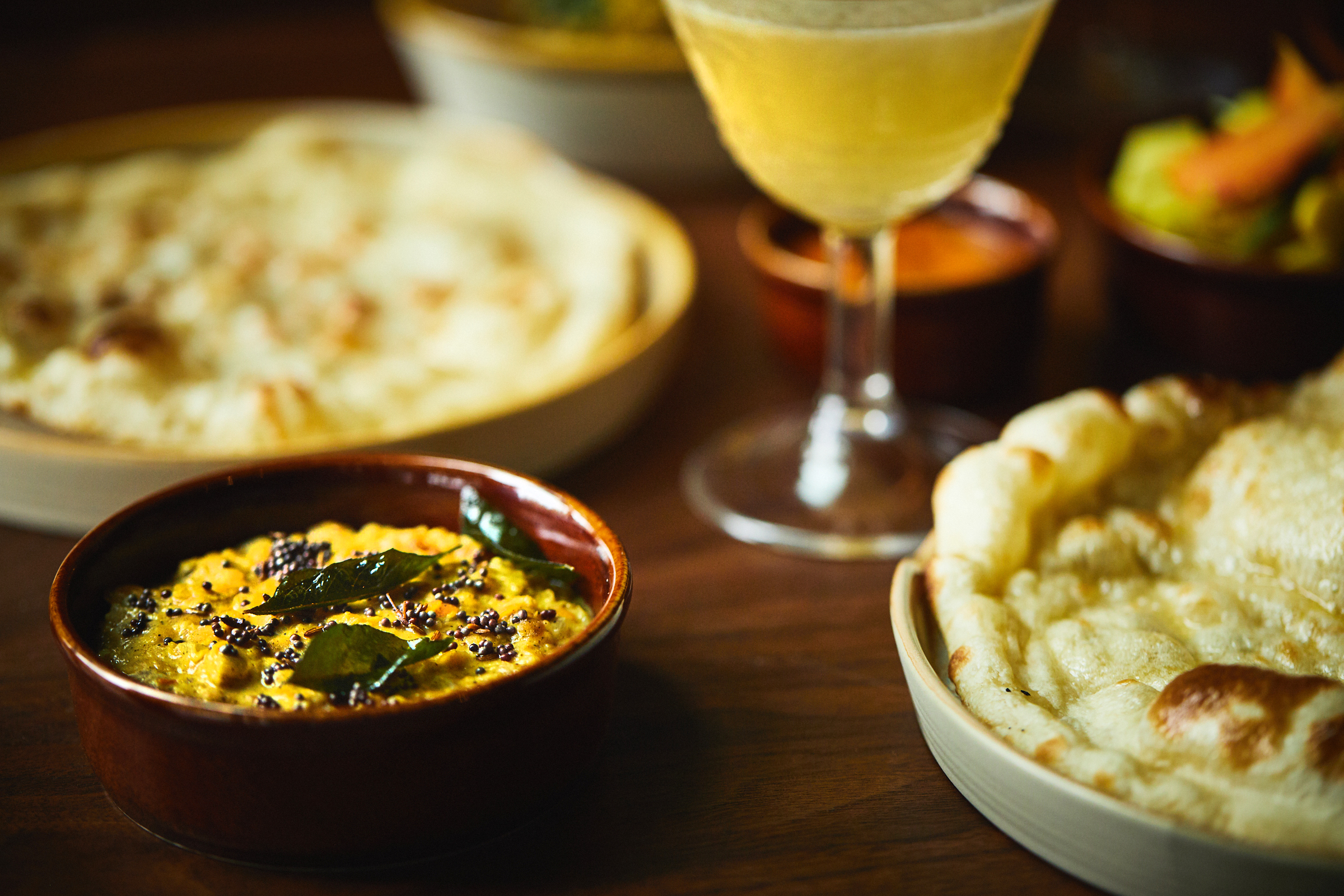 An assortment of Sri Lankan dishes, along with a yellow-colored cocktail.