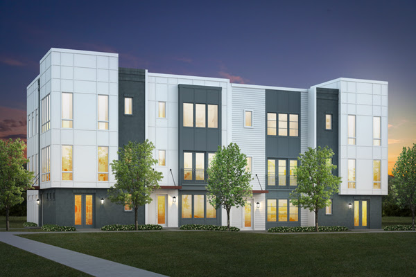 A white townhome development with trees and green grass in front.