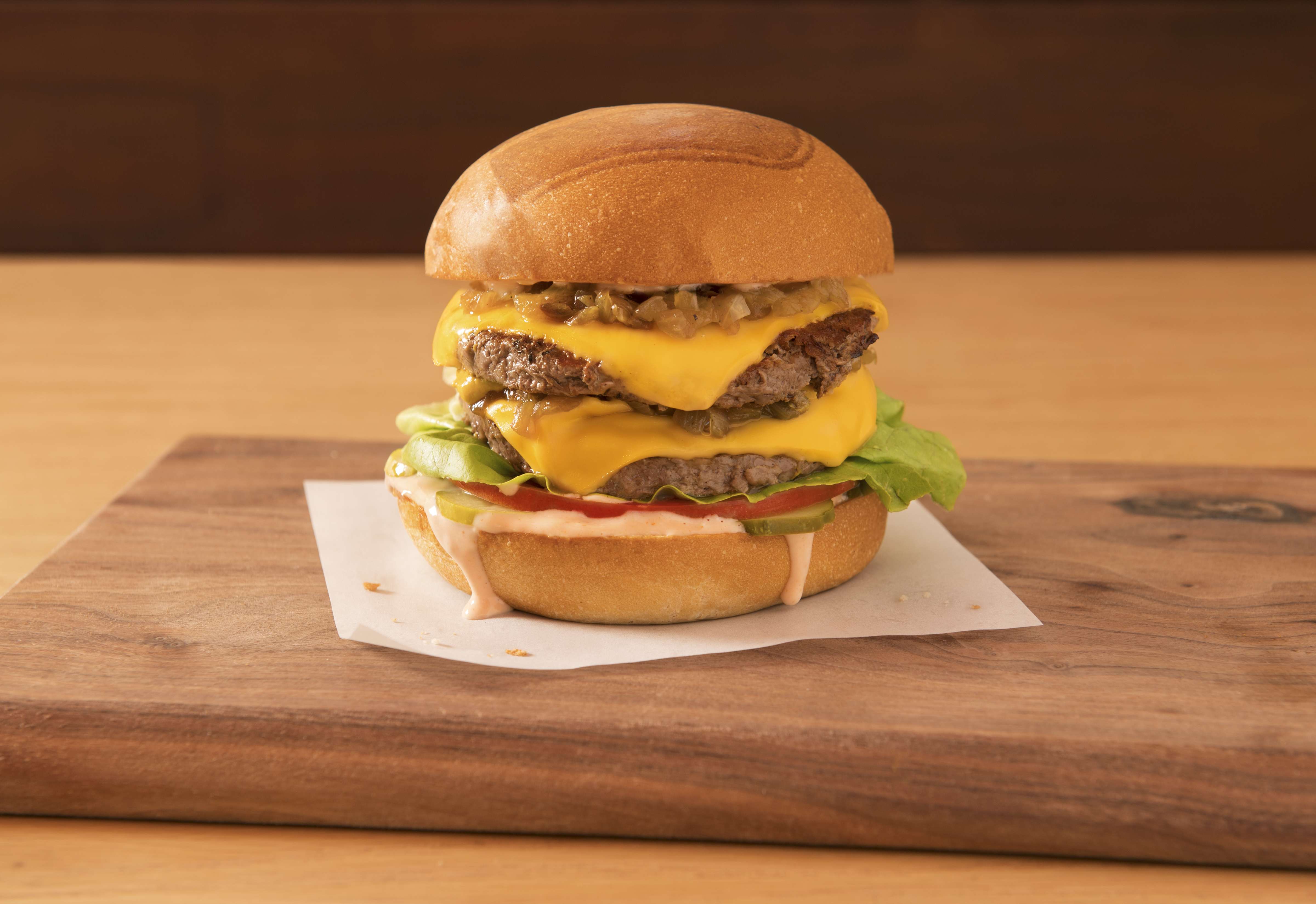 A double stack cheeseburger on a wooden board