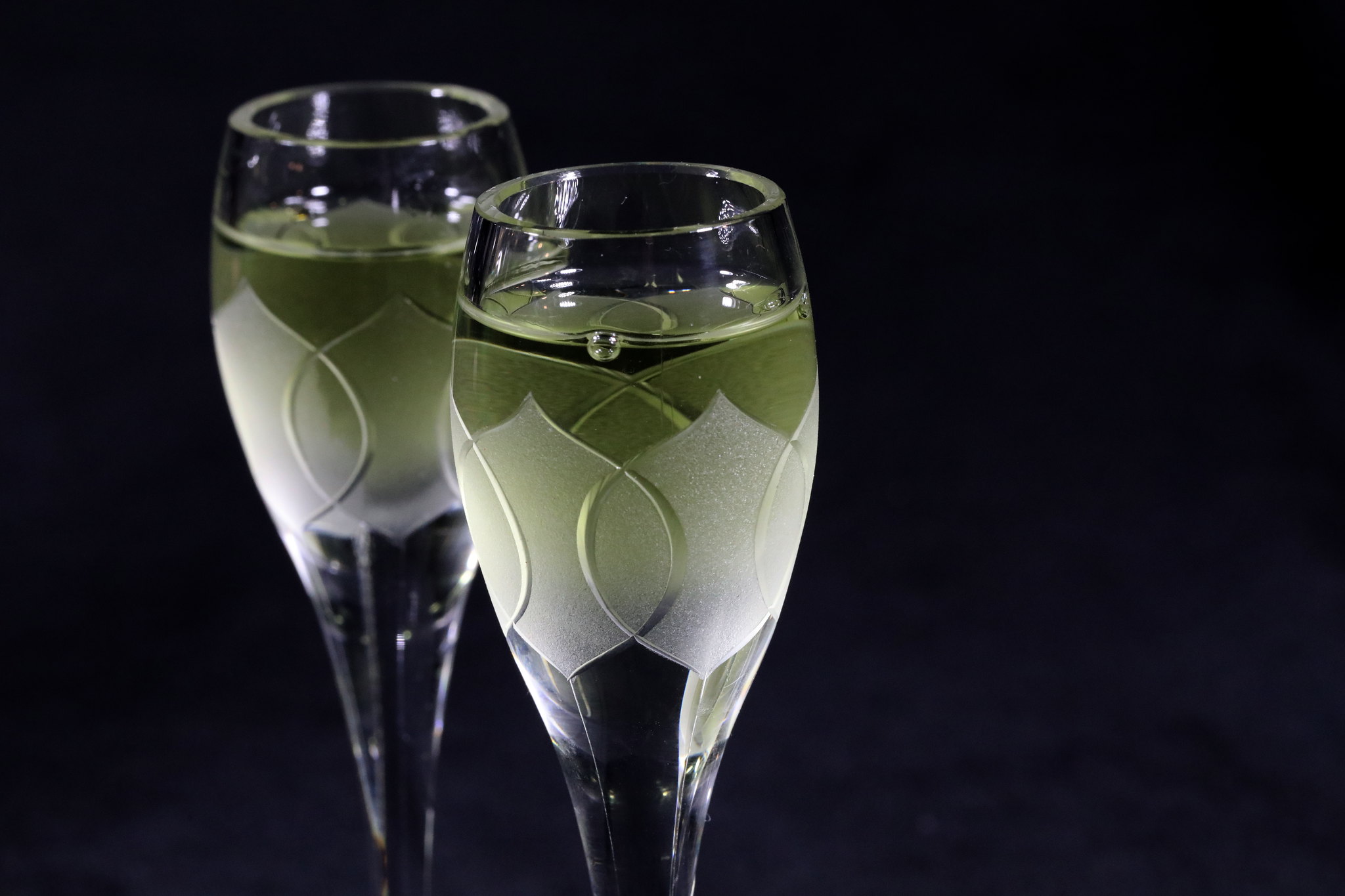 Two small glasses filled with Chartreuse on a black background 