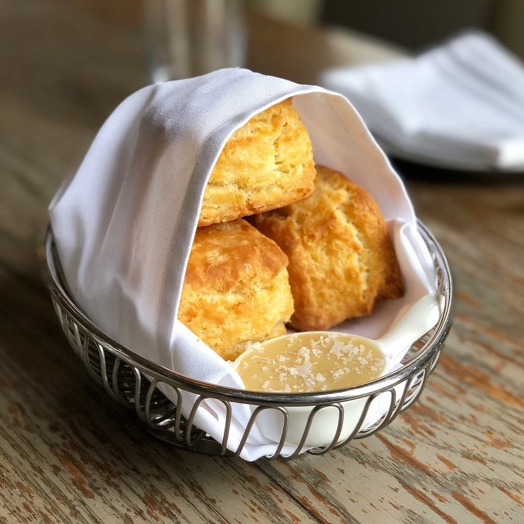 A basket of biscuits wrapped in a white napkin.