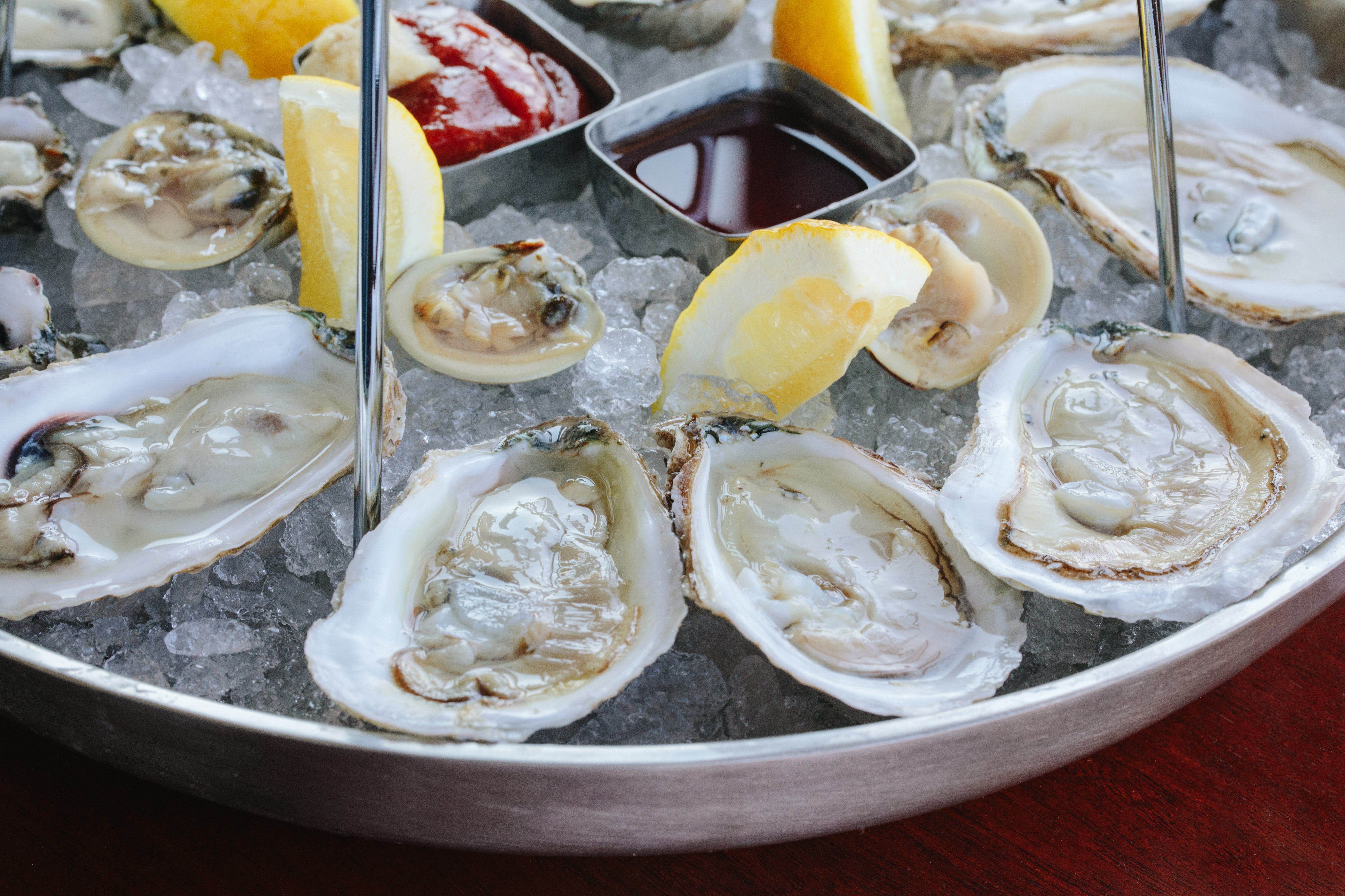 A plate of oysters on the half shell from Reelhouse oyster bar. The oysters are accompanied by mignonette, cocktail sauce, and lemon wedges.