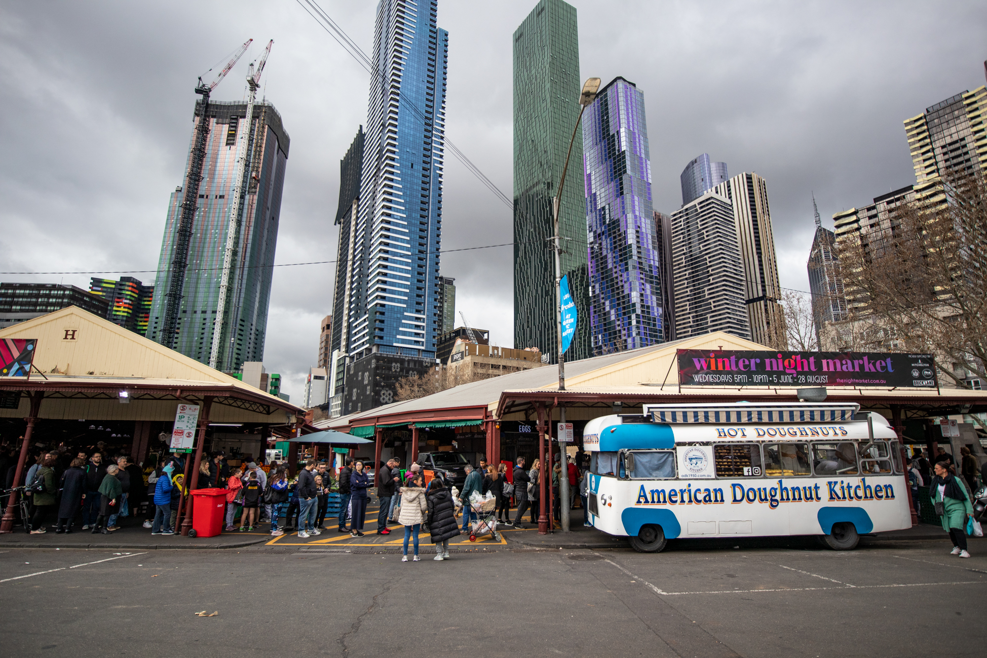 The American Doughnut Kitchen bus parks outside the Queen Victoria Market, beneath the Melbourne skyline
