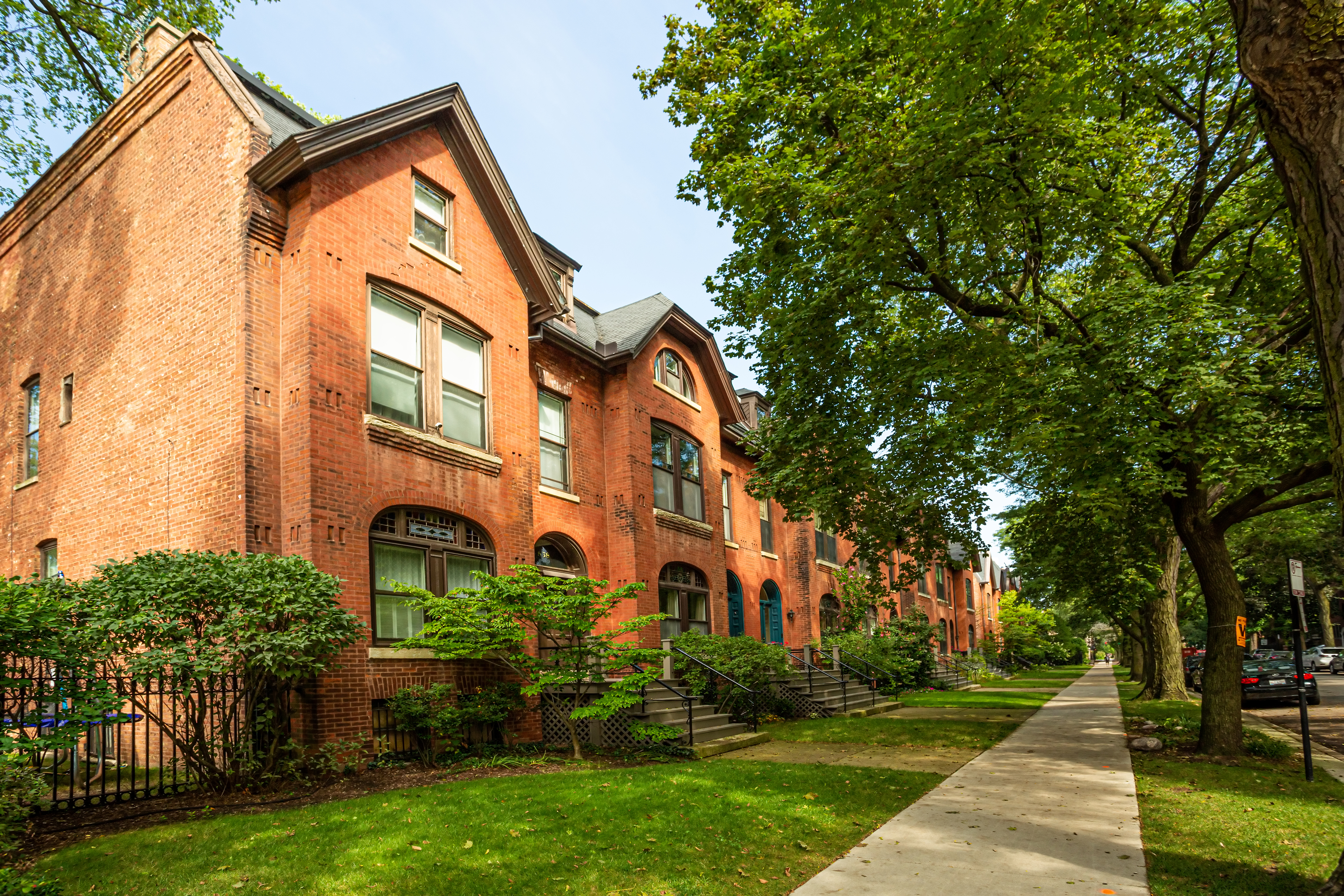 A row of brick houses in a neighborhood with a tree-lined parkway